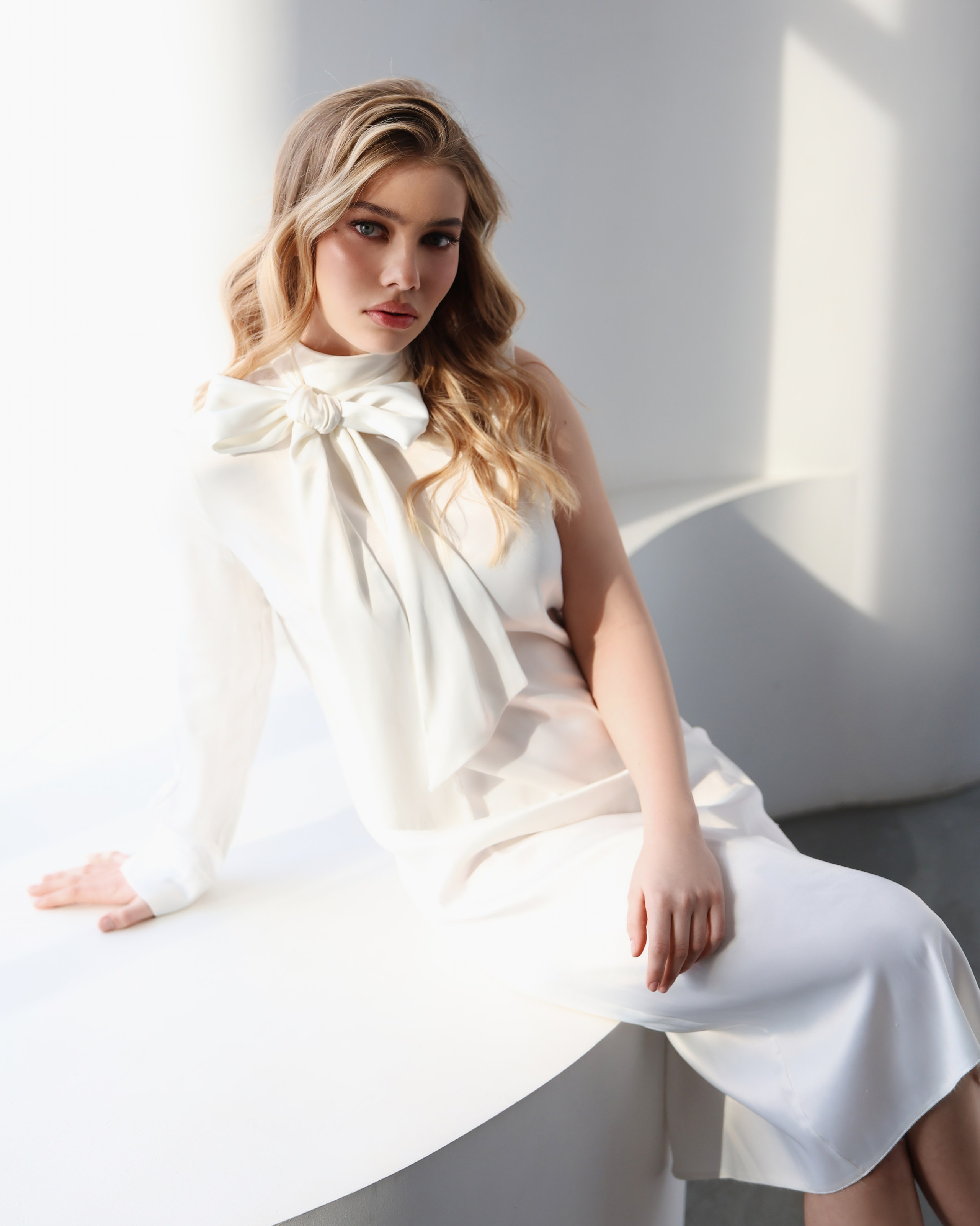Фотосессия Челябинск в студии для девушки - стильная студийная фотосессия в светлом интерьере с мягким естественным светом, девушка в белом элегантном платье позирует на светлом диване на фоне деревянной стены, минималистичная эстетика, чистый фон, женственная поза, профессиональная фотосессия в студии Челябинск, идеи для фотосессии девушки, вдохновение для съемки, современная портретная съемка, красивая фотосессия для личного бренда, фотосессия для инстаграм, нежные и дорогие визуалы, услуги фотографа Челябинск, студийная фотосъемка для девушек, позирование и стиль для фотосессии, съемка в светлой студии
