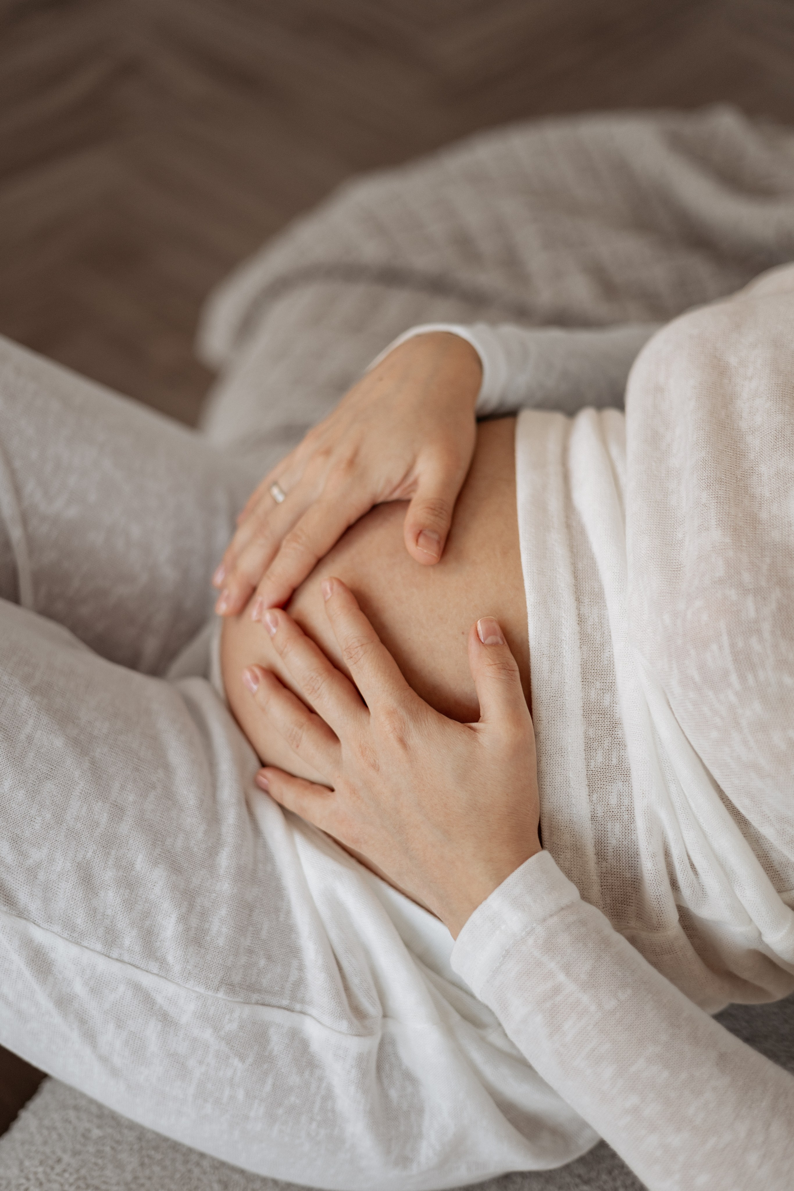 Нежность материнства: крупный план рук будущей мамы, бережно сложенных в форме сердца на ее животе на 32 неделе.