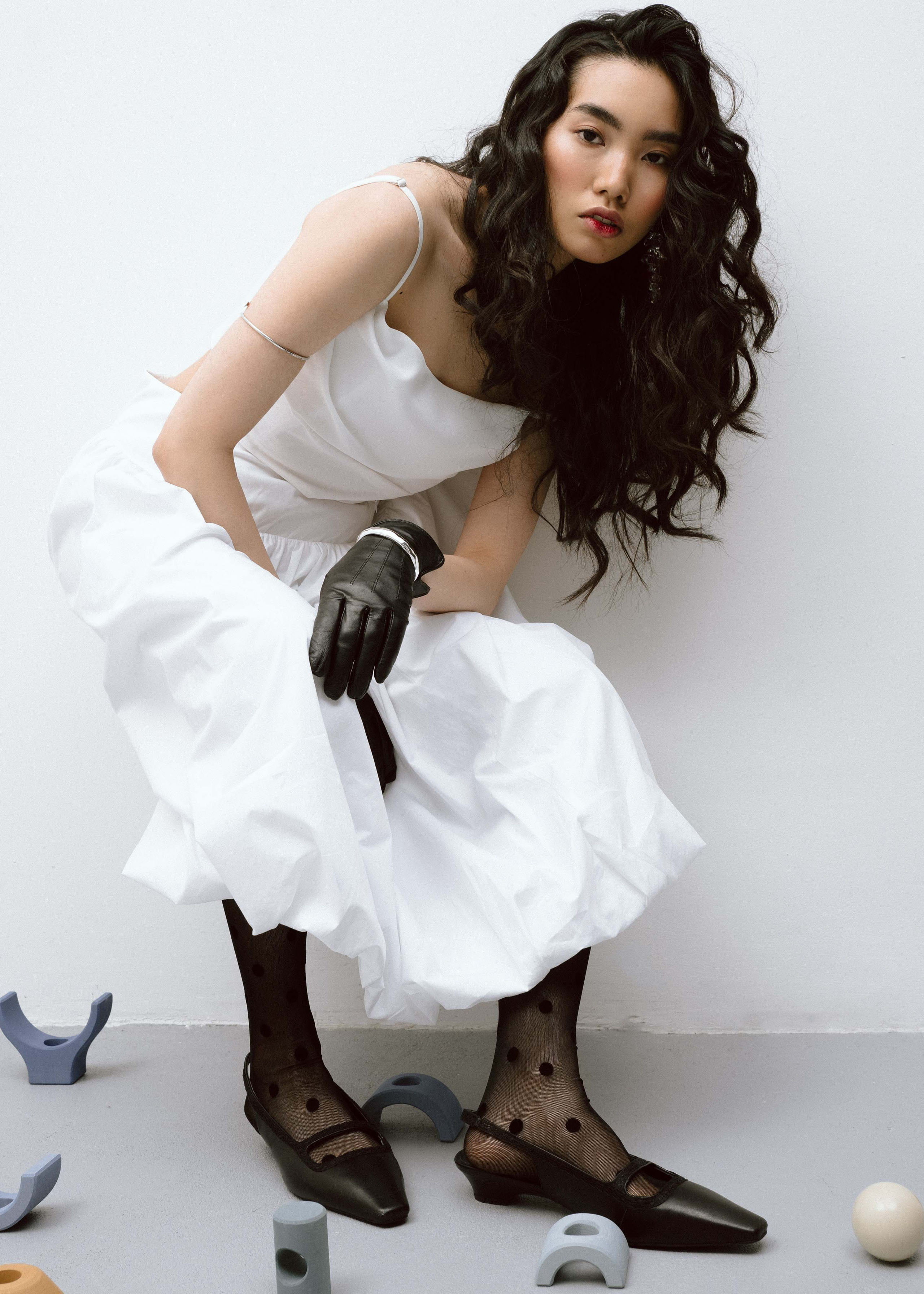 Девушка модель в необычной позе на фотосессии в студии для бренда одежды