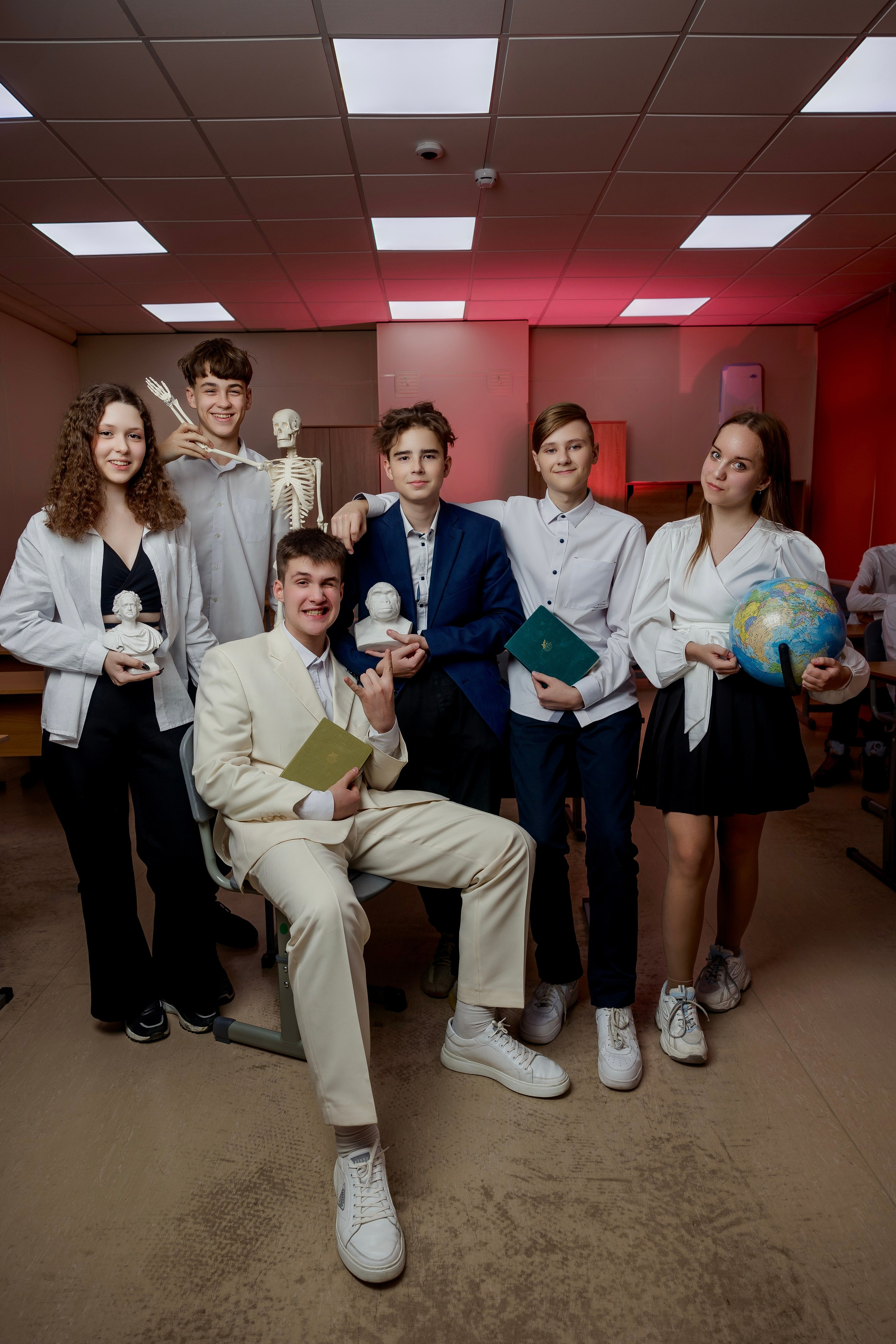 Компания юношей и девушек стоят с глобусом и скелетом