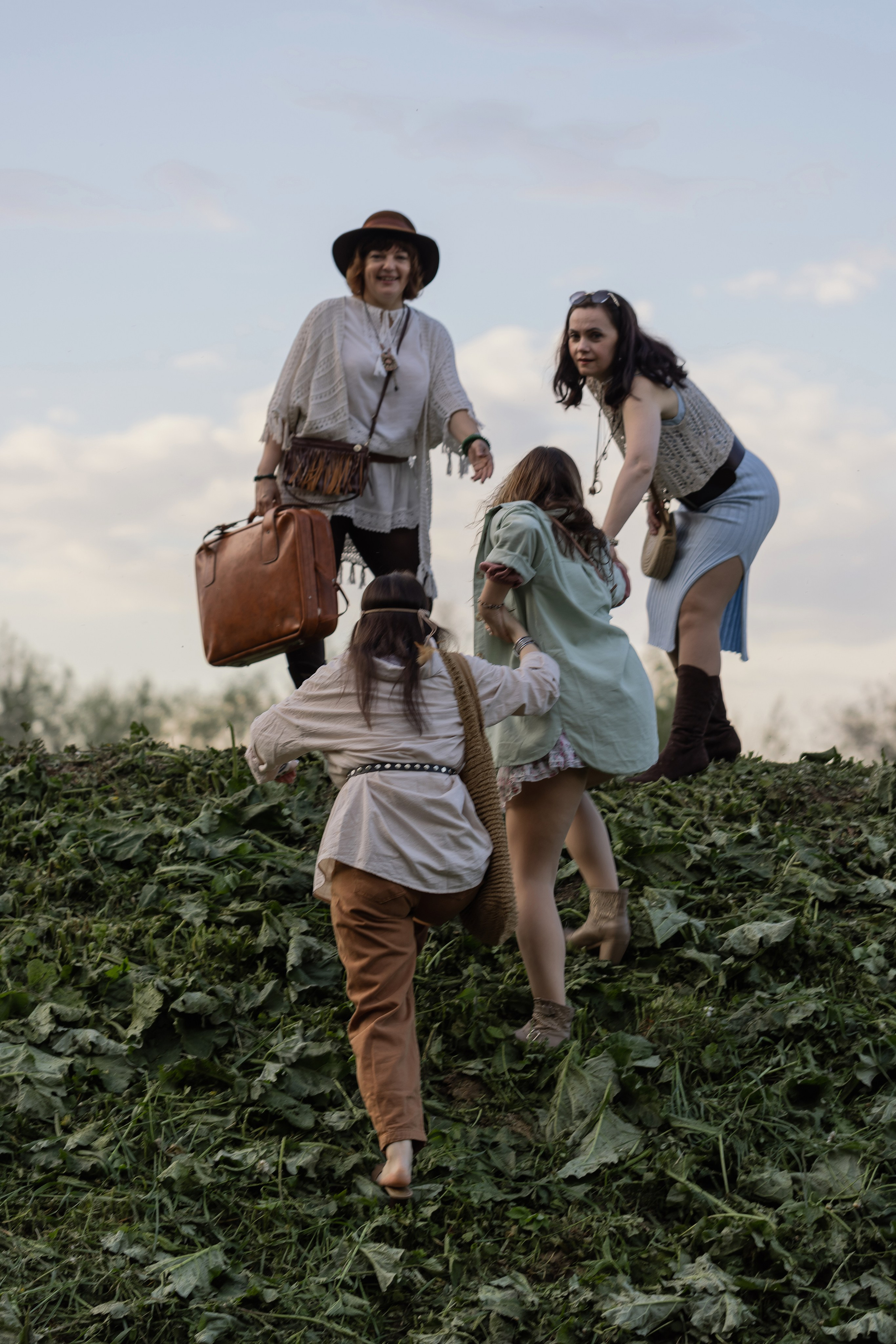 Девушки карабкаются в гору, в руках у одной чемодан