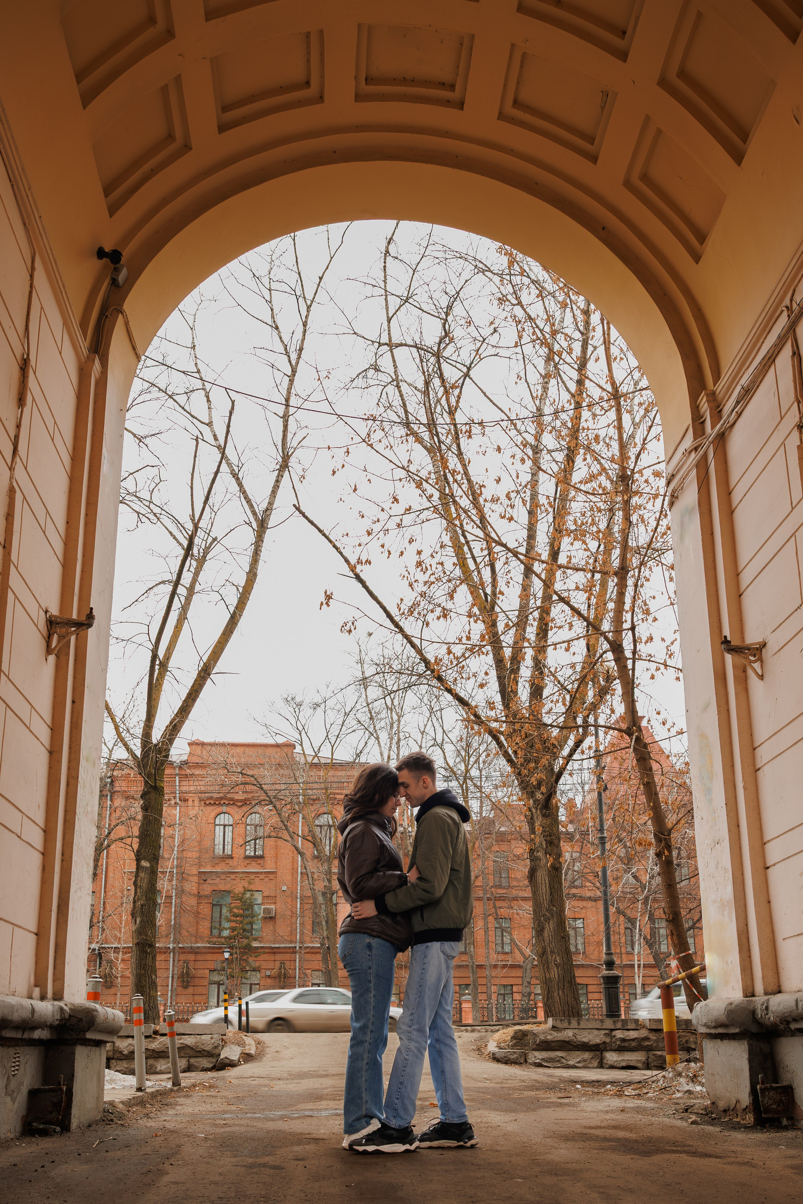Фотосессия Love Story в историческом центре Хабаровска: пара в арке старинного здания на фоне красного кирпича. Профессиональная уличная съемка для влюбленных