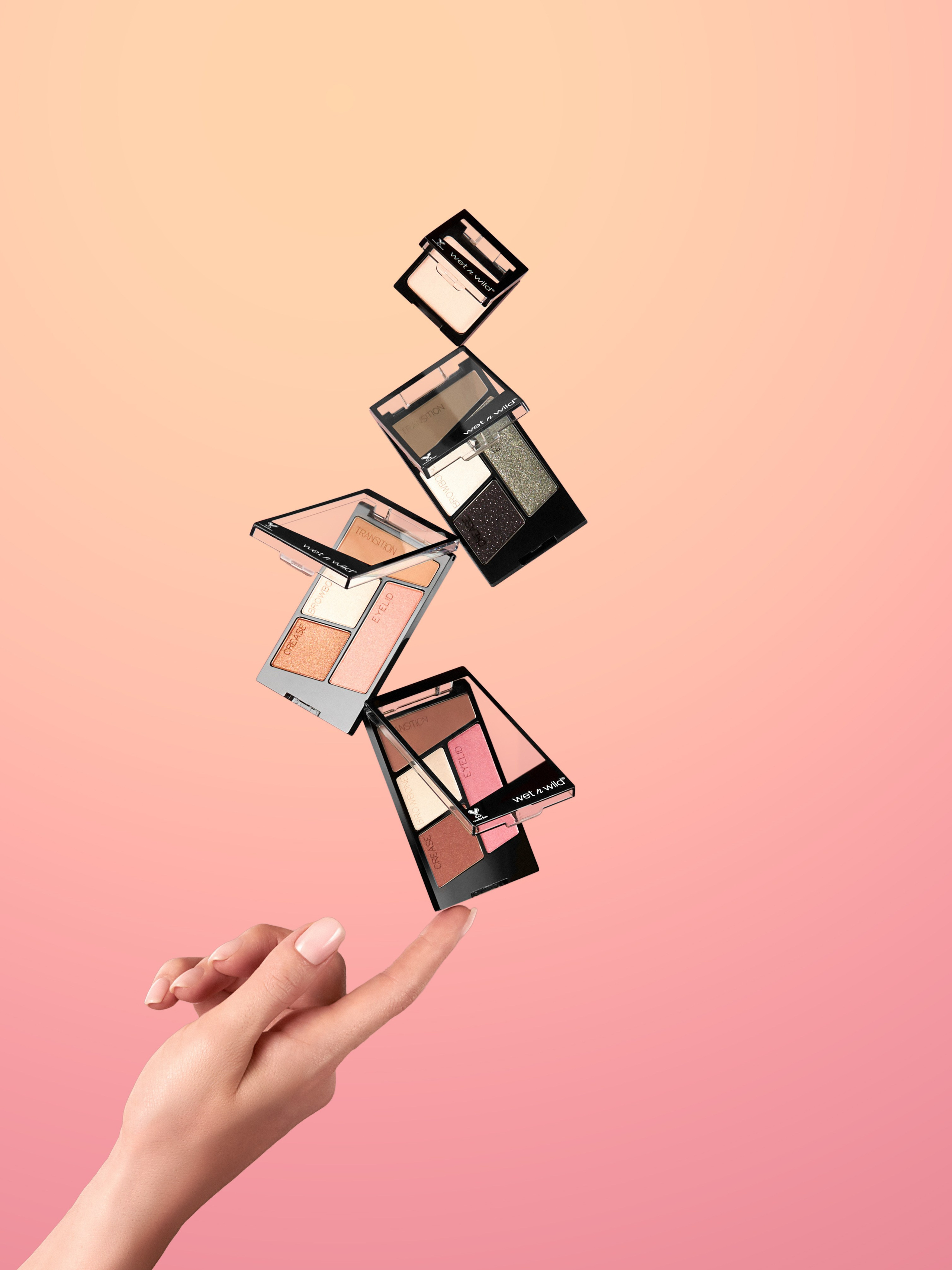 Рука девушки модели на одном пальце держит балансирующую башенку из теней для век