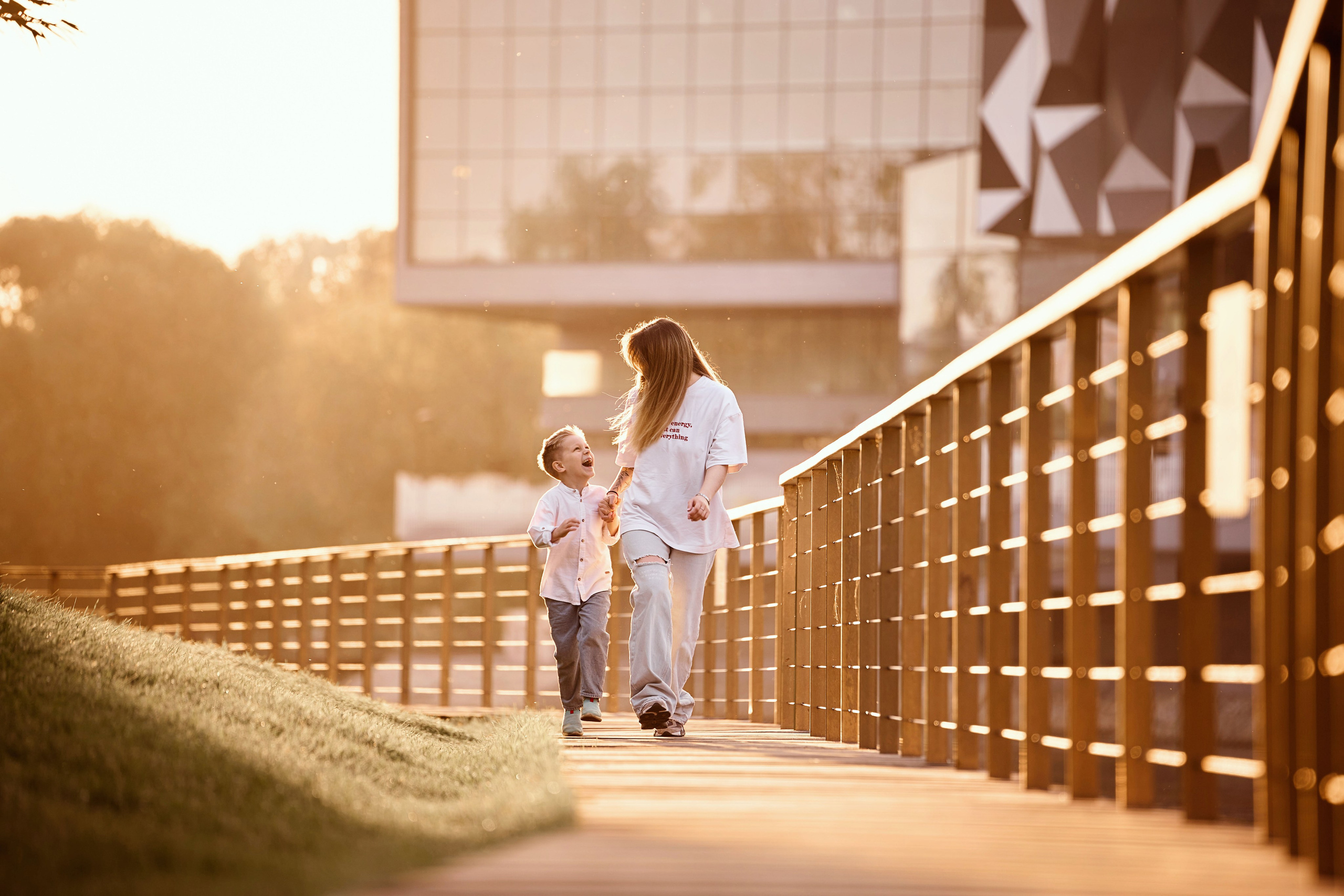 мама с ребёнком на закате идут вдоль пруда на ВДНХ держась за руки