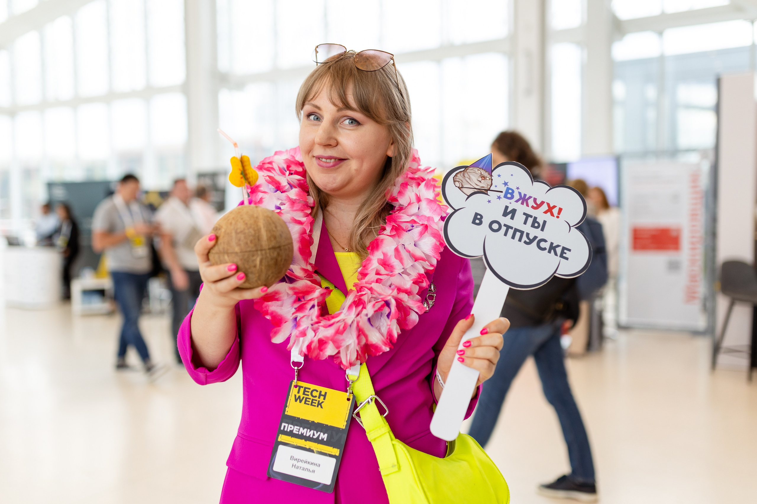 Девушка в розовом платье держит руках кокос и табличку с надписью вжух и ты в отпуске
