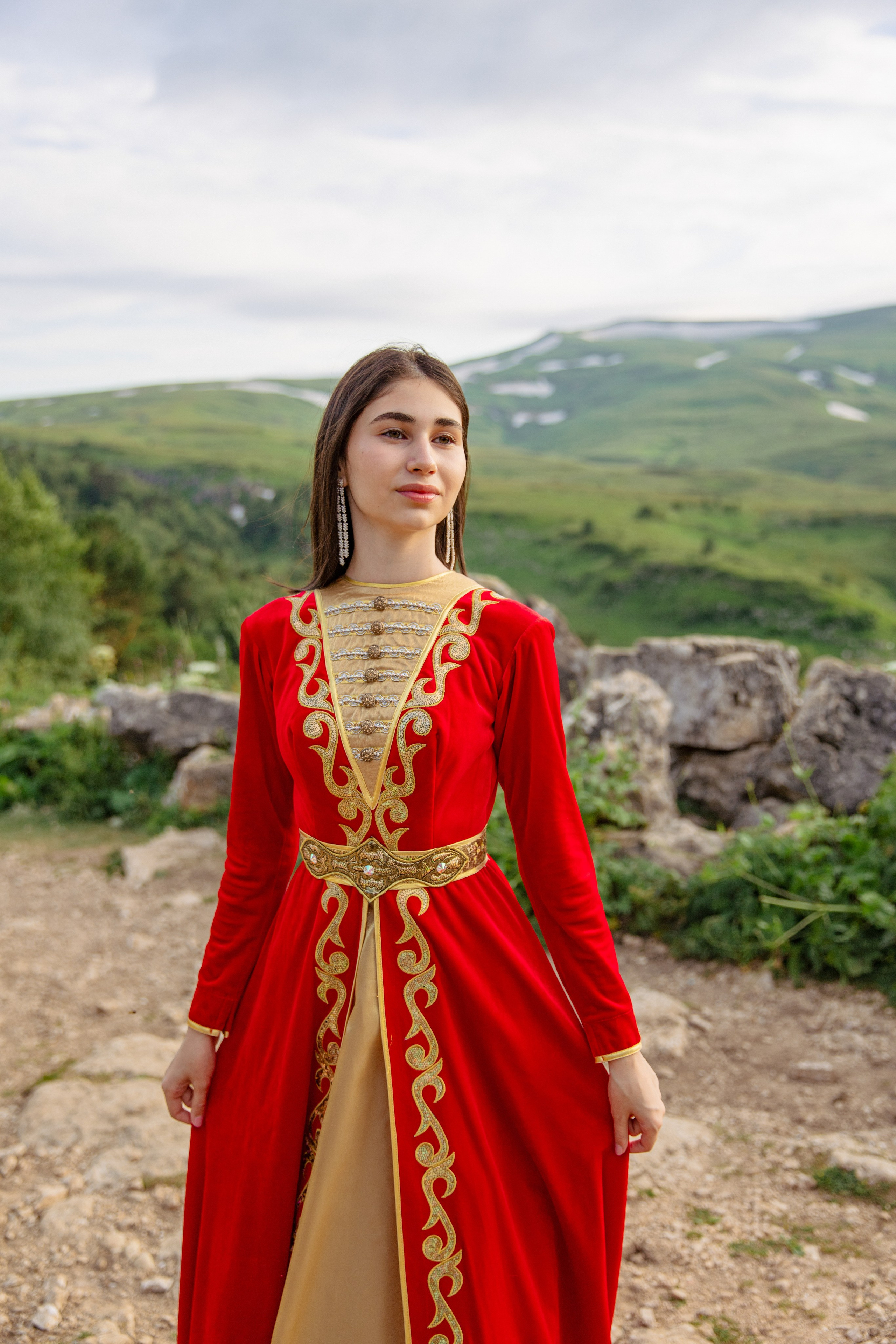 Очаровательная адыгейка в национальной одежде , позирующая на фоне удачно подобранных гор