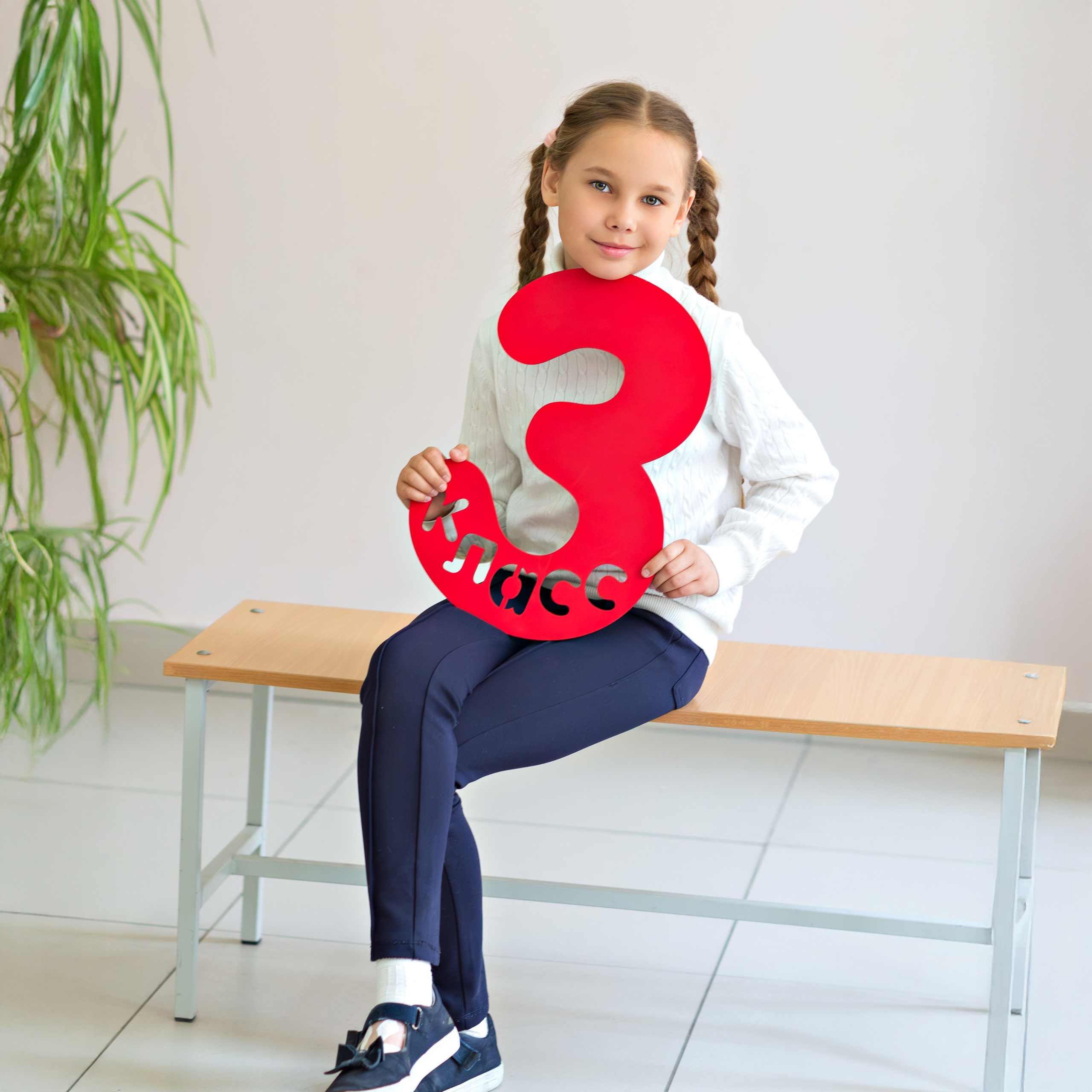 Девочка держит красную цифру «3» на школьной фотосессии, портрет