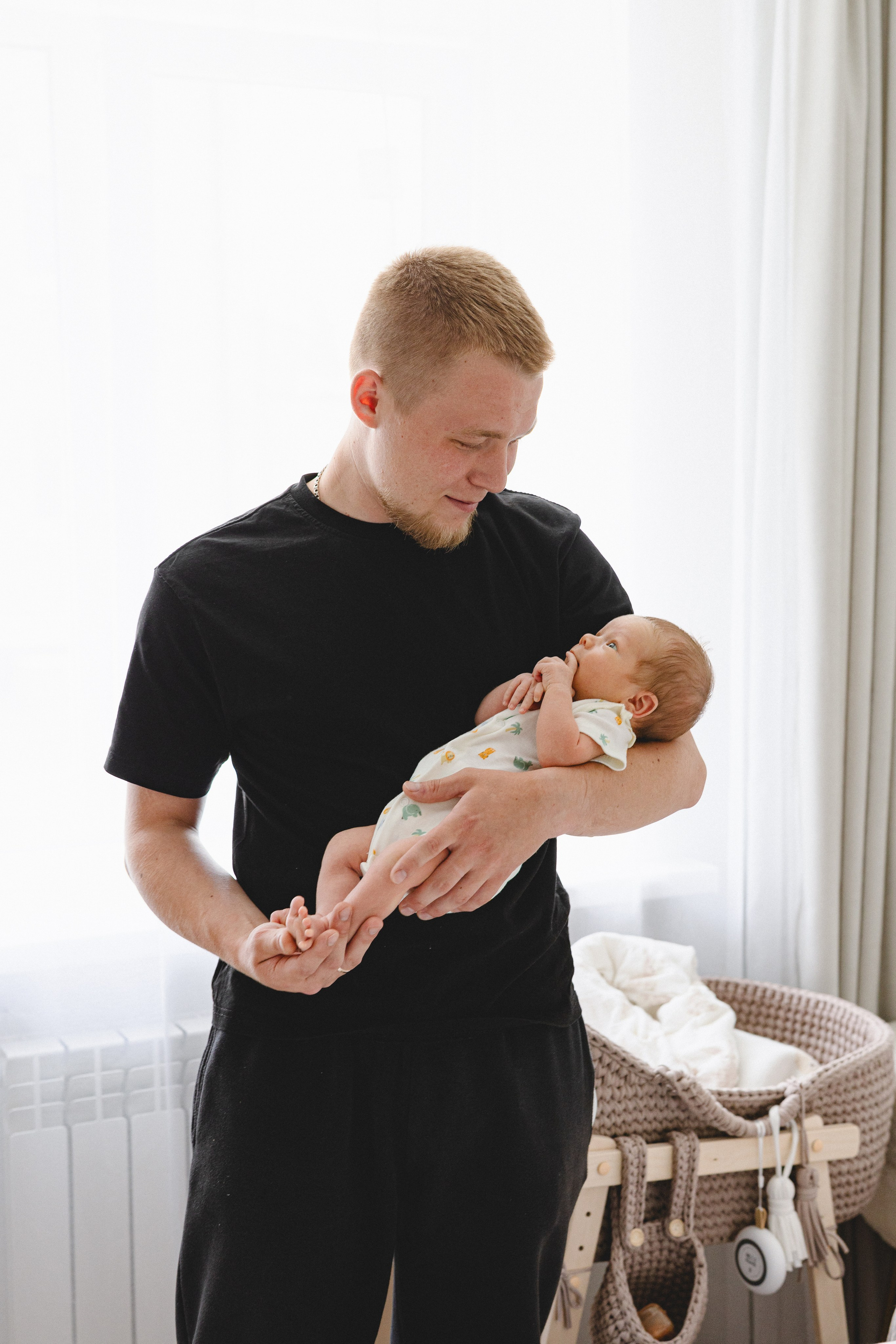 Father holding his newborn beside a bright window