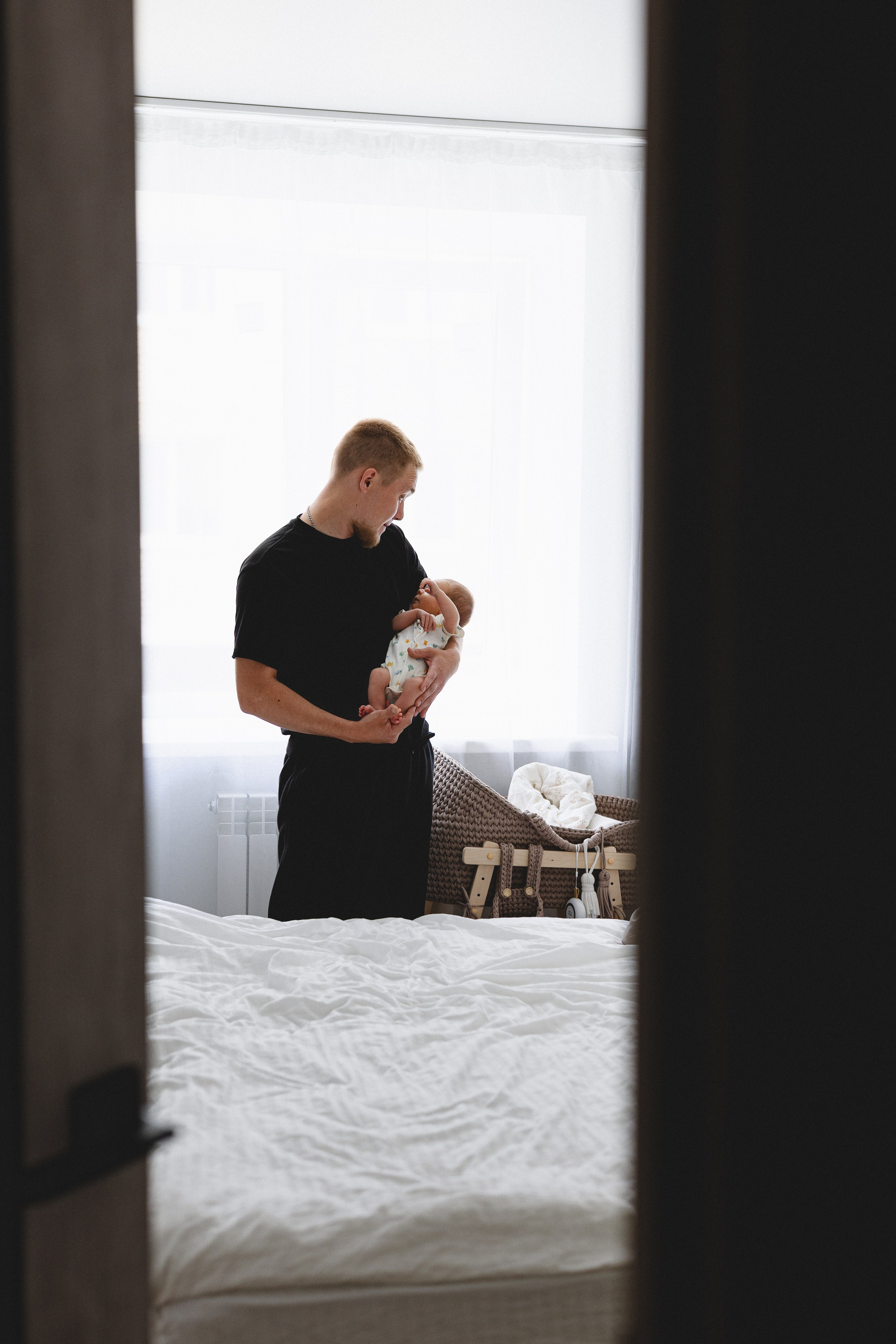 Father holding his newborn baby in the bedroom doorway