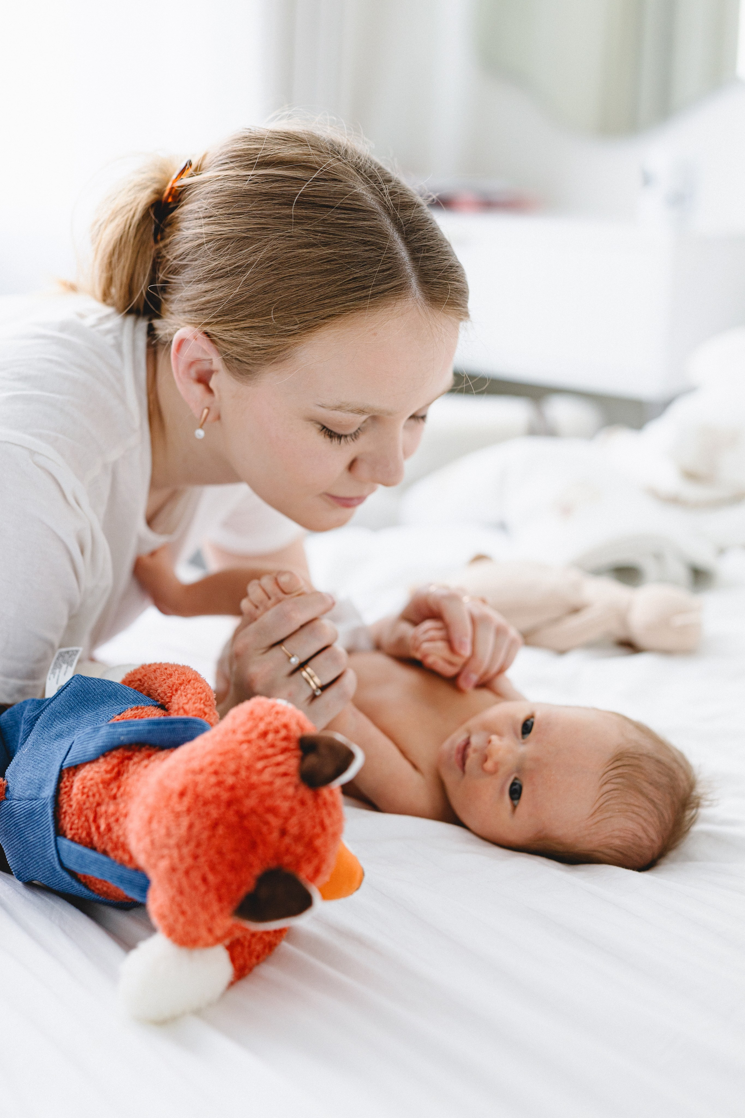 Mother playing with her newborn and a soft fox toy
