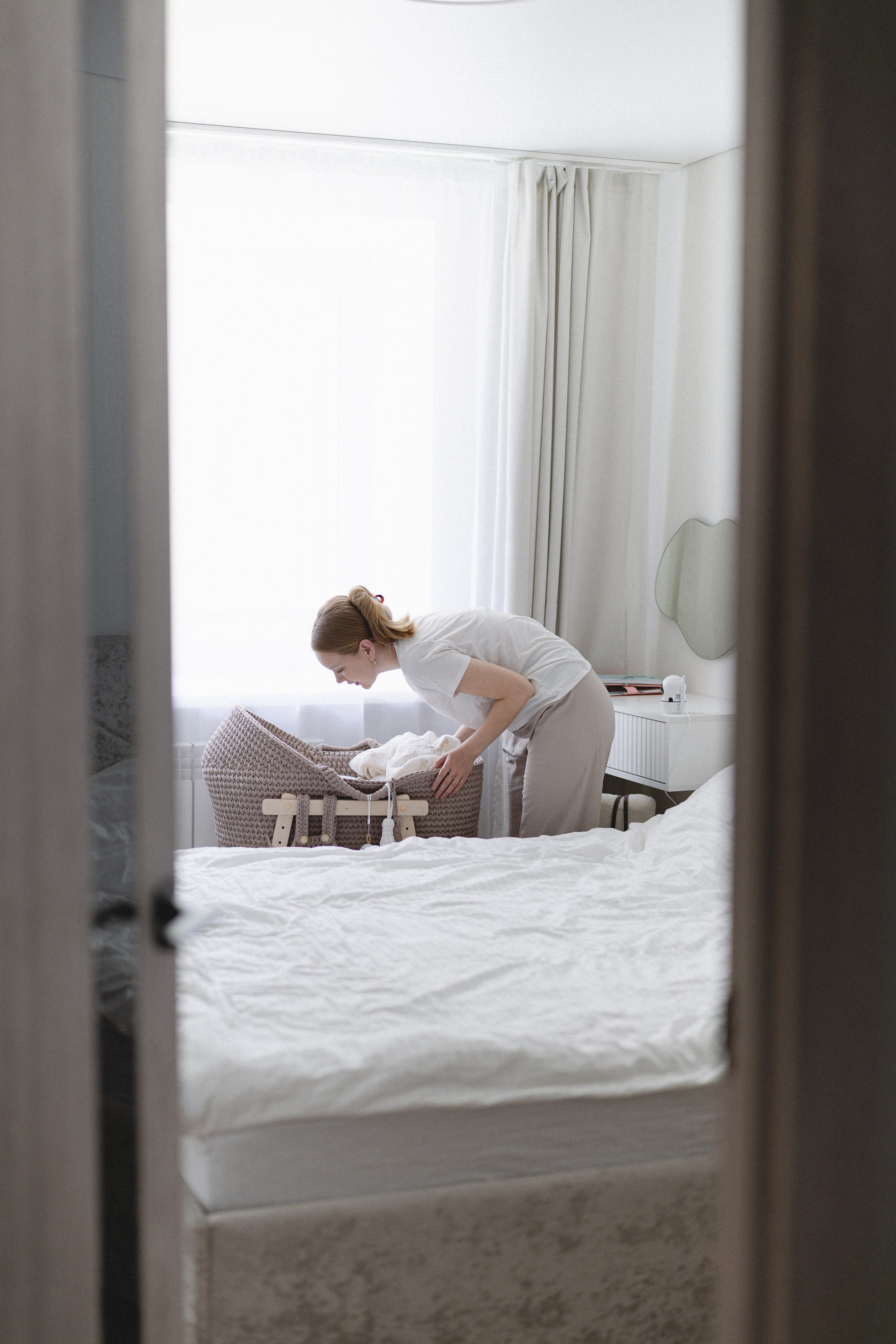 Mother leaning over her newborn’s bassinet at home