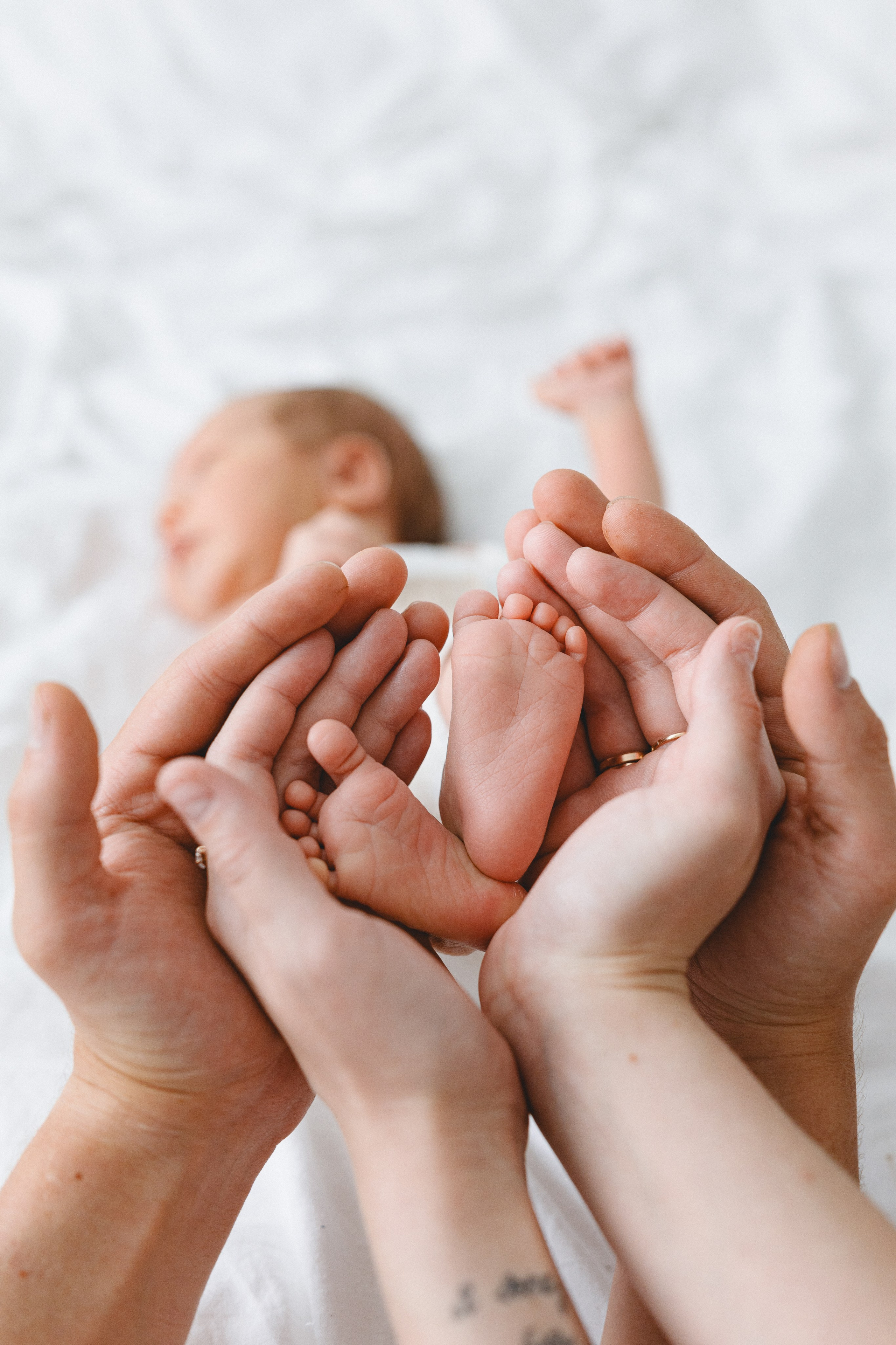 Close-up of tiny newborn feet in the parents’ hands