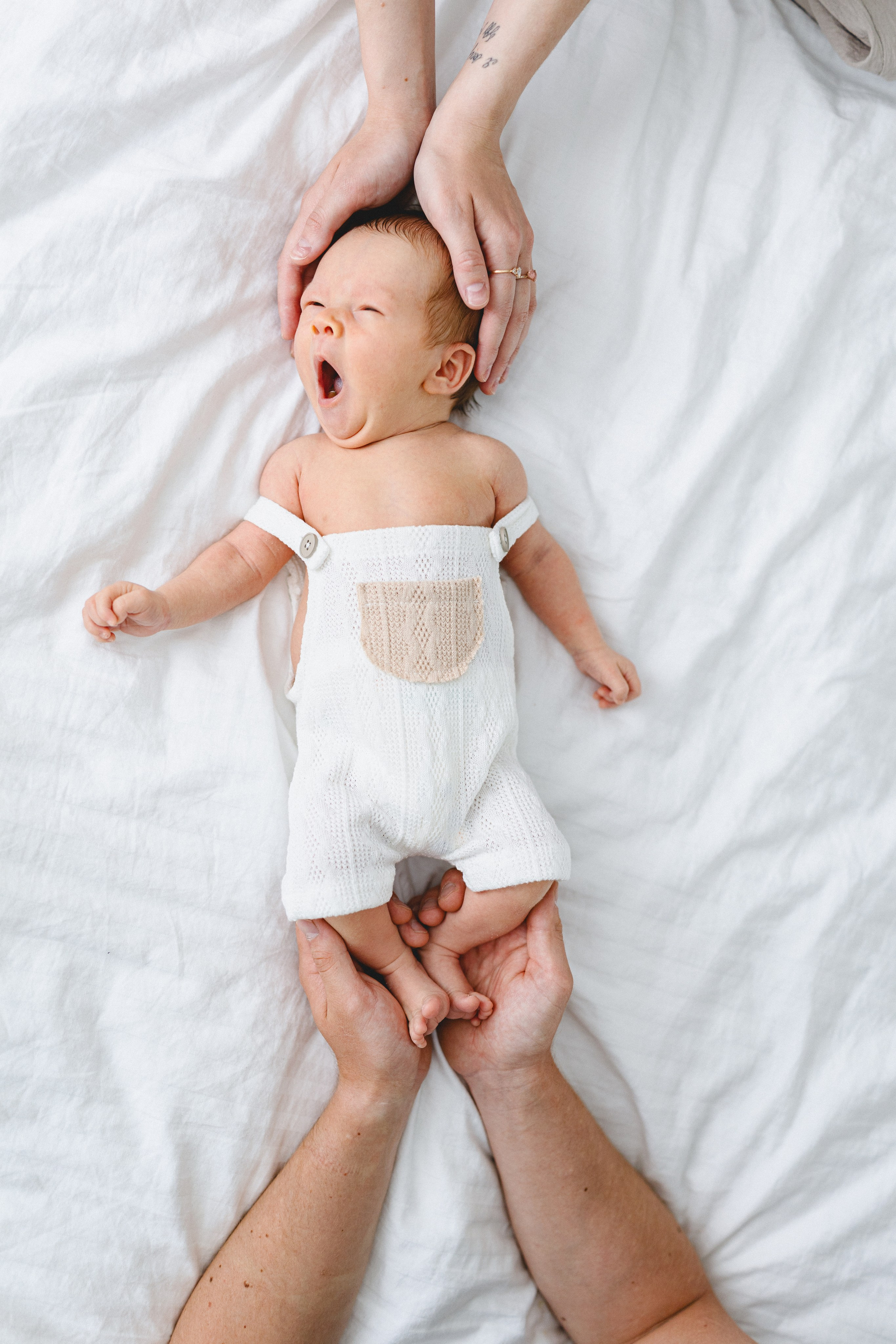 Yawning newborn baby held gently by the parents