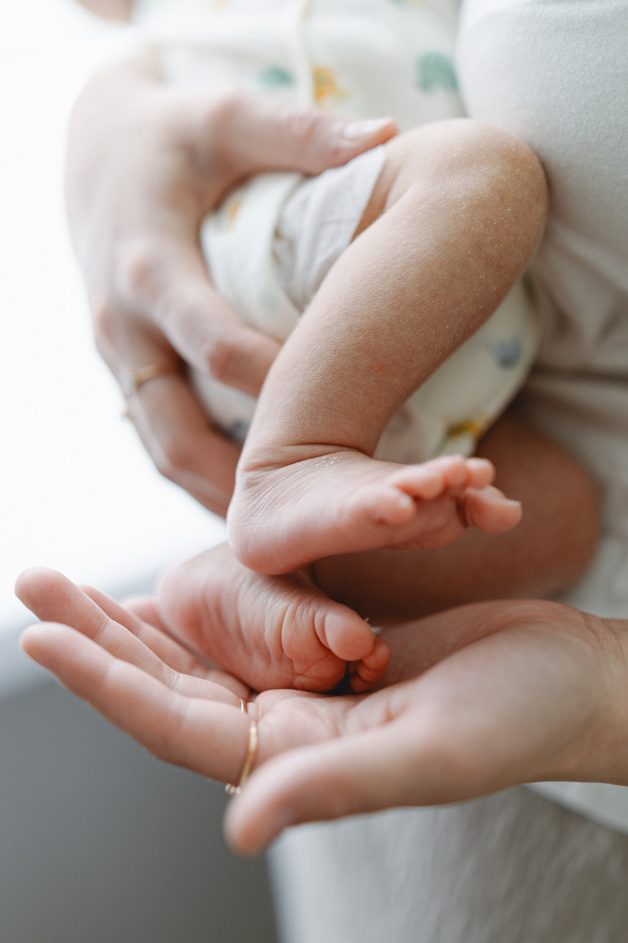 Tiny newborn feet resting in a parent’s hands