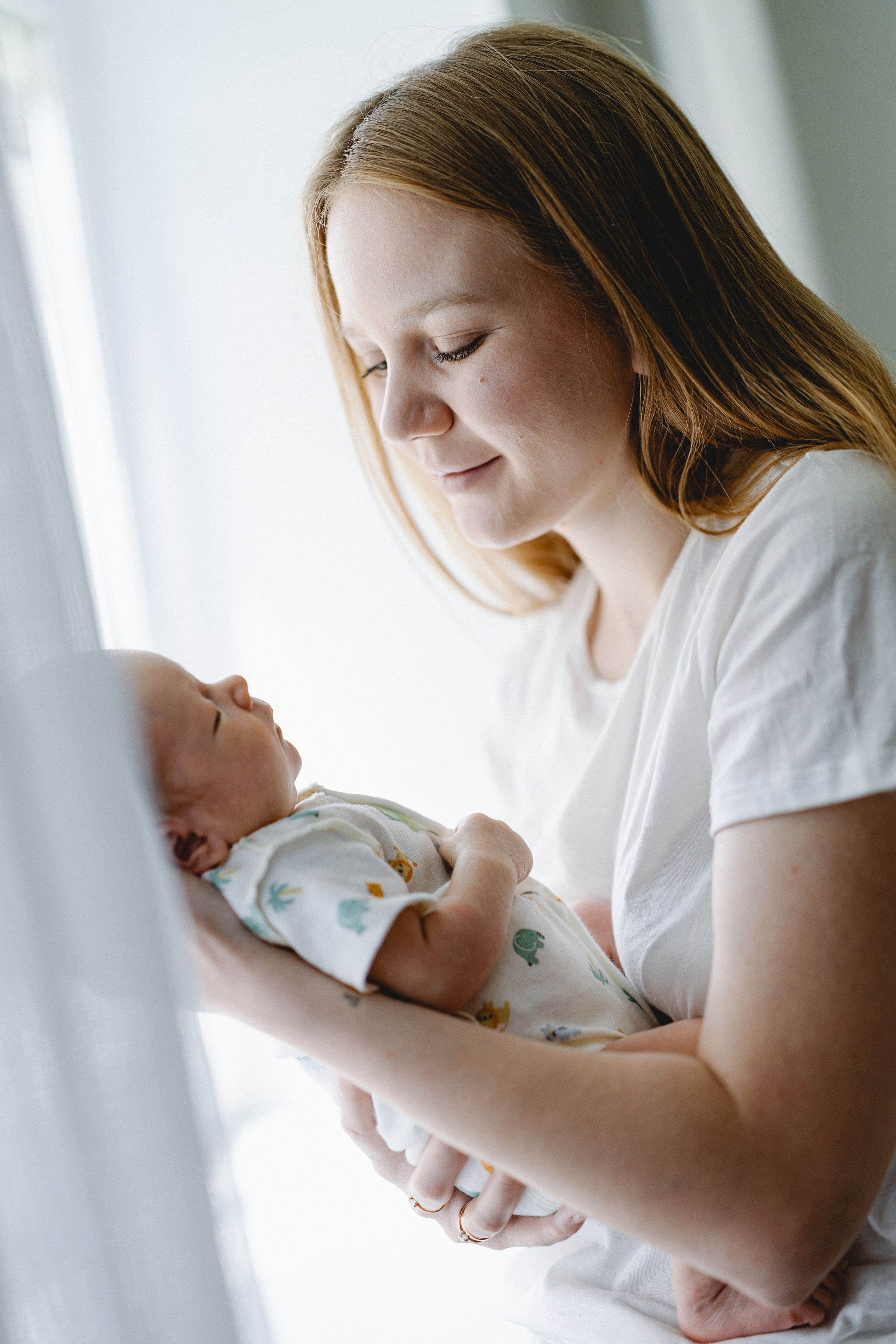Mother smiling at her newborn beside the window