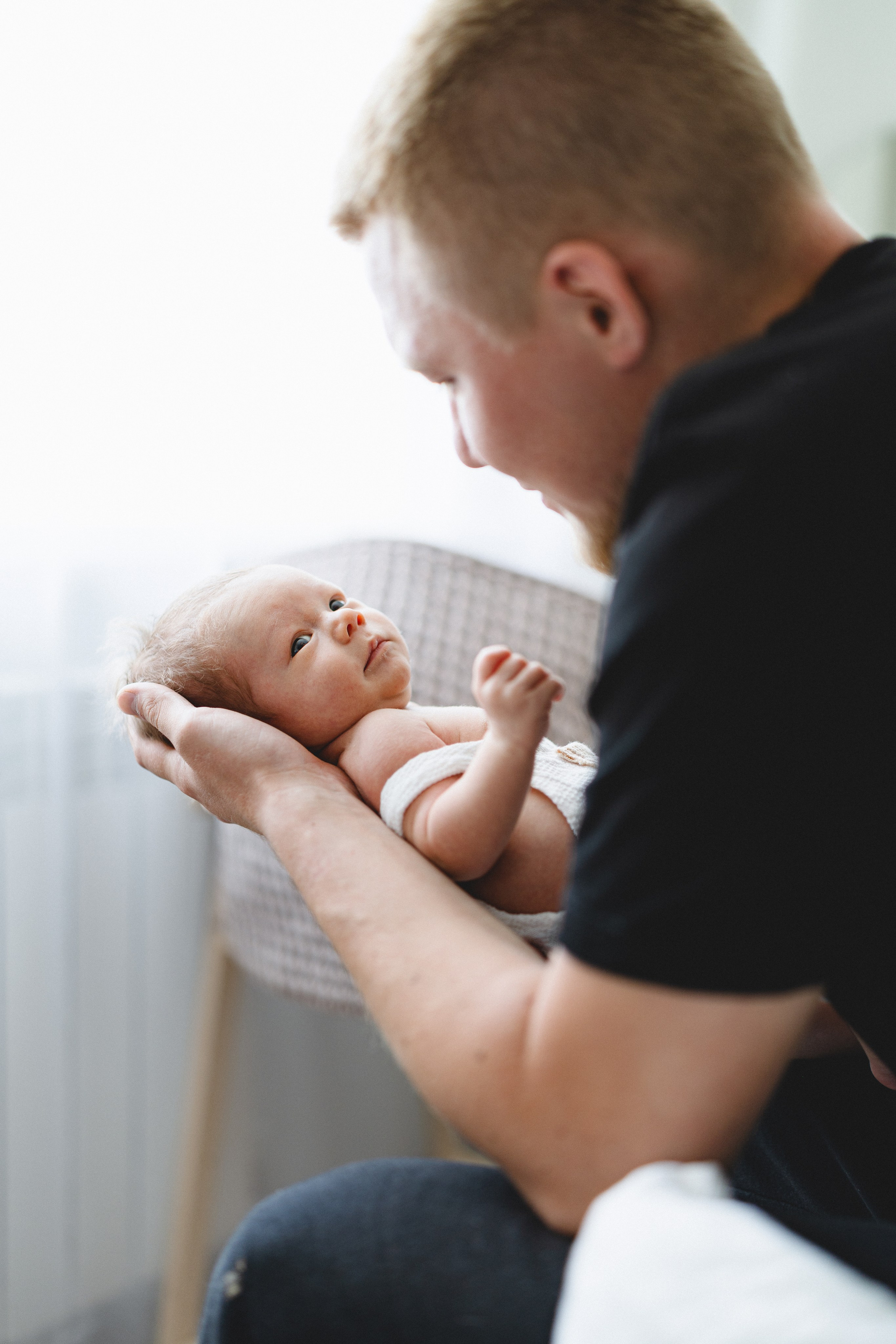 Father gently cradling his newborn baby at home