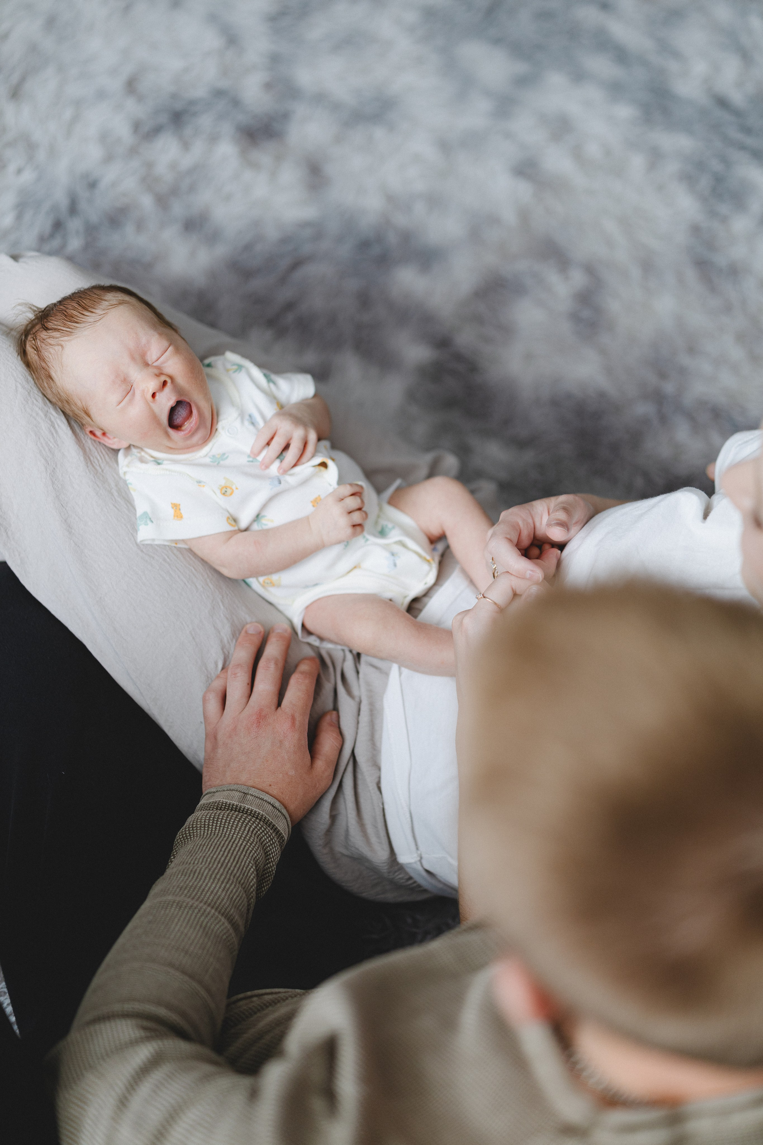 Newborn baby yawning while resting with the parents