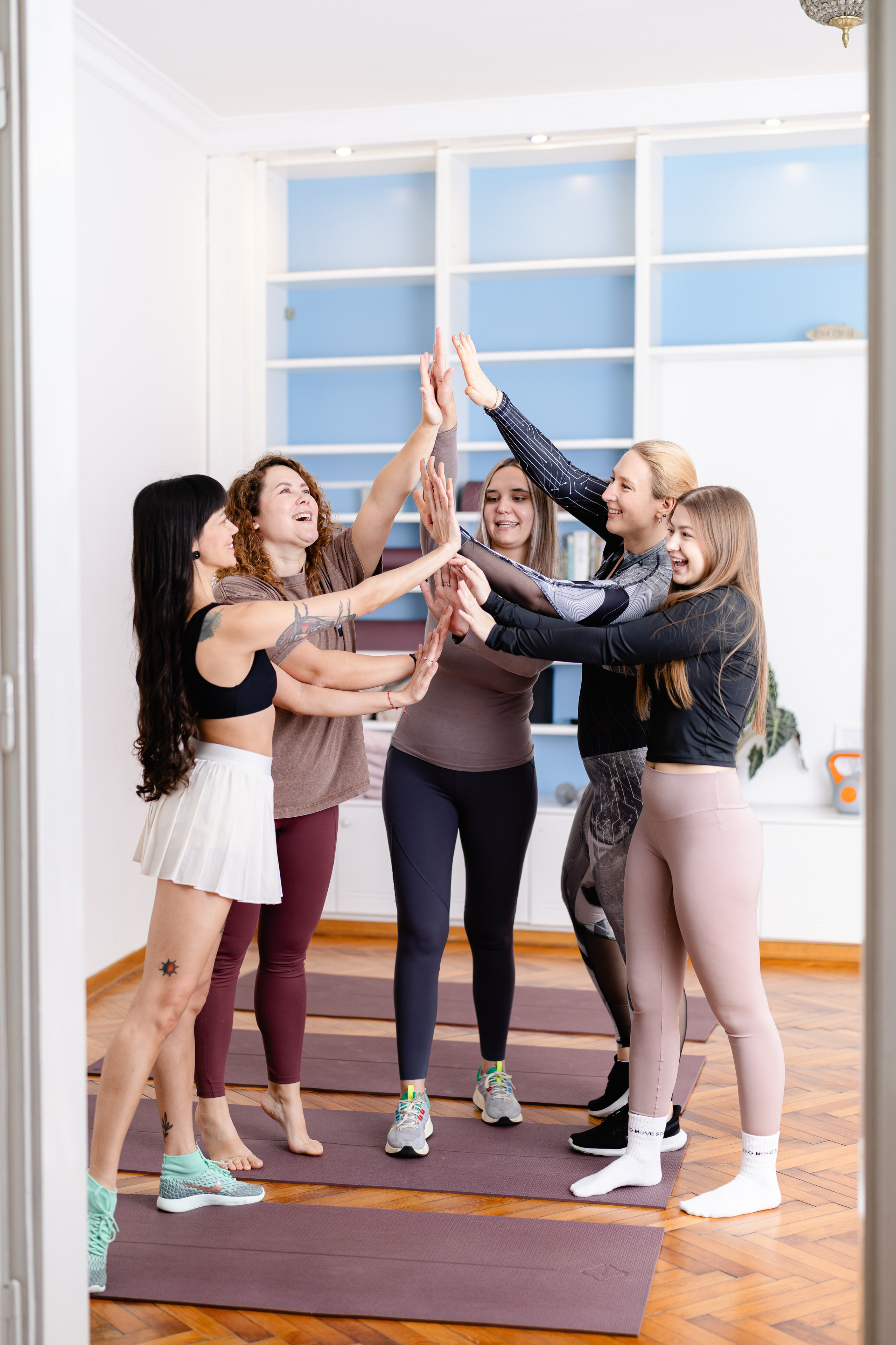 A group of young women in sportswear standing in a circle giving a shared high five