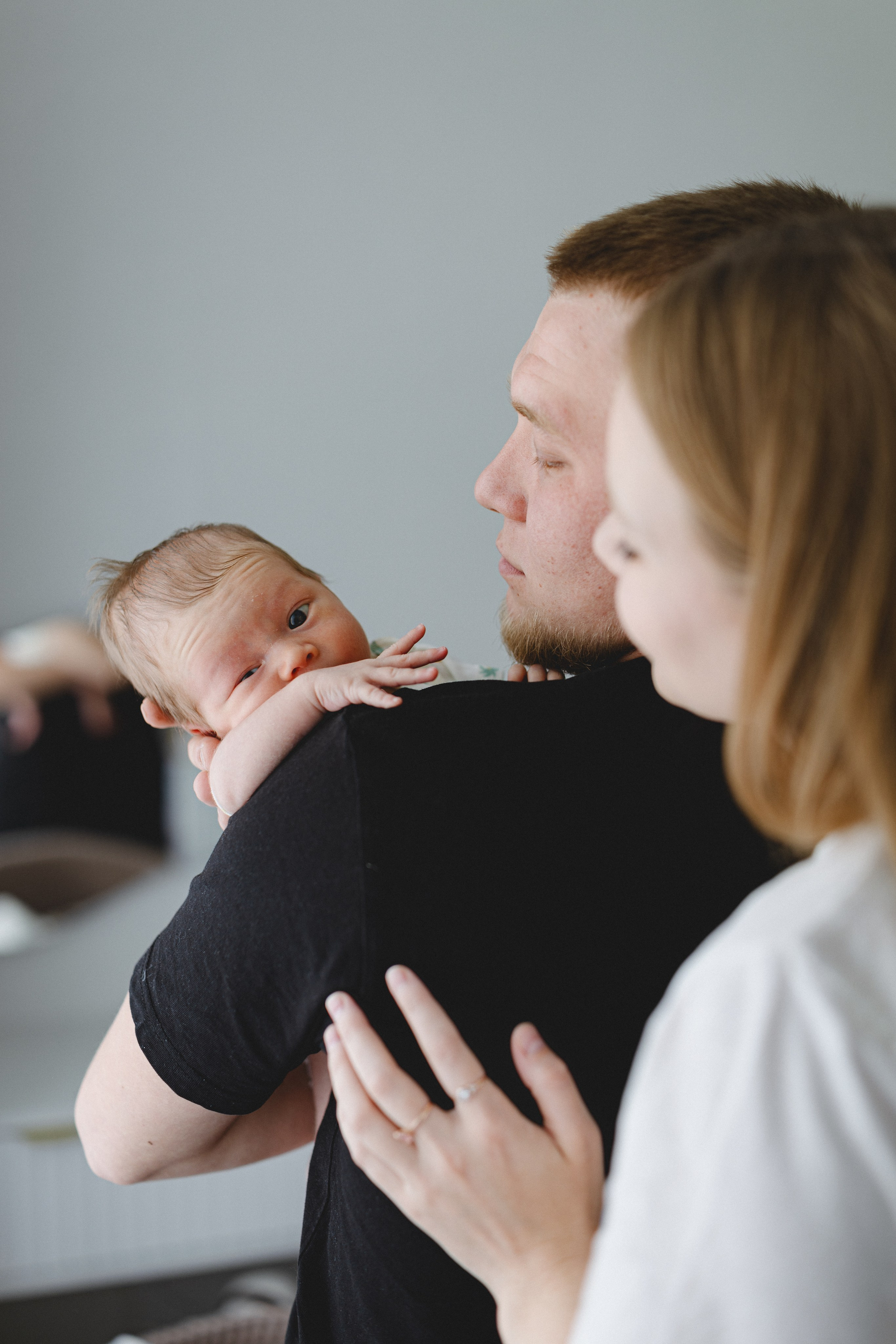 Newborn resting on the father’s shoulder beside the mother