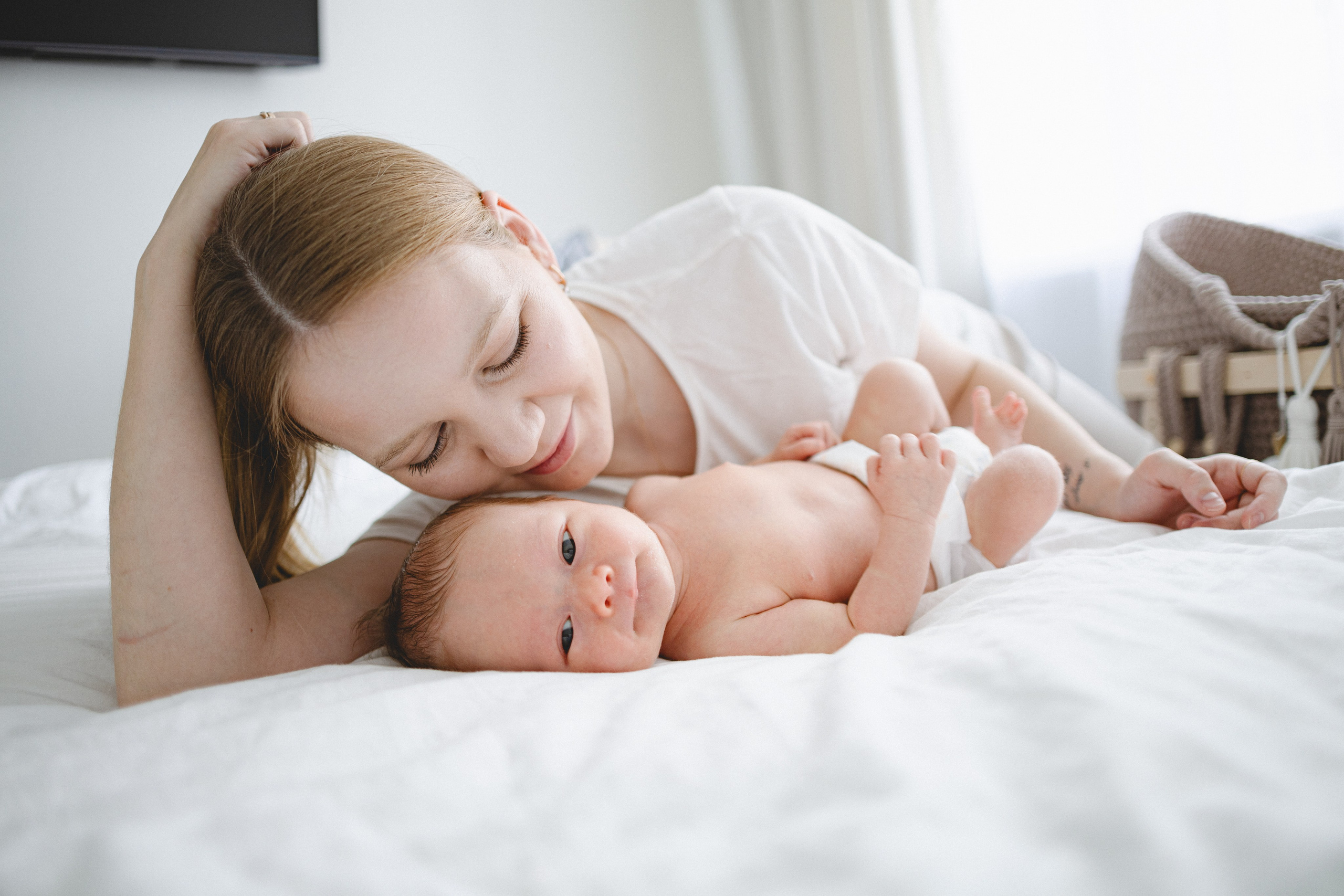 Mother lying beside her newborn and looking into the baby’s eyes