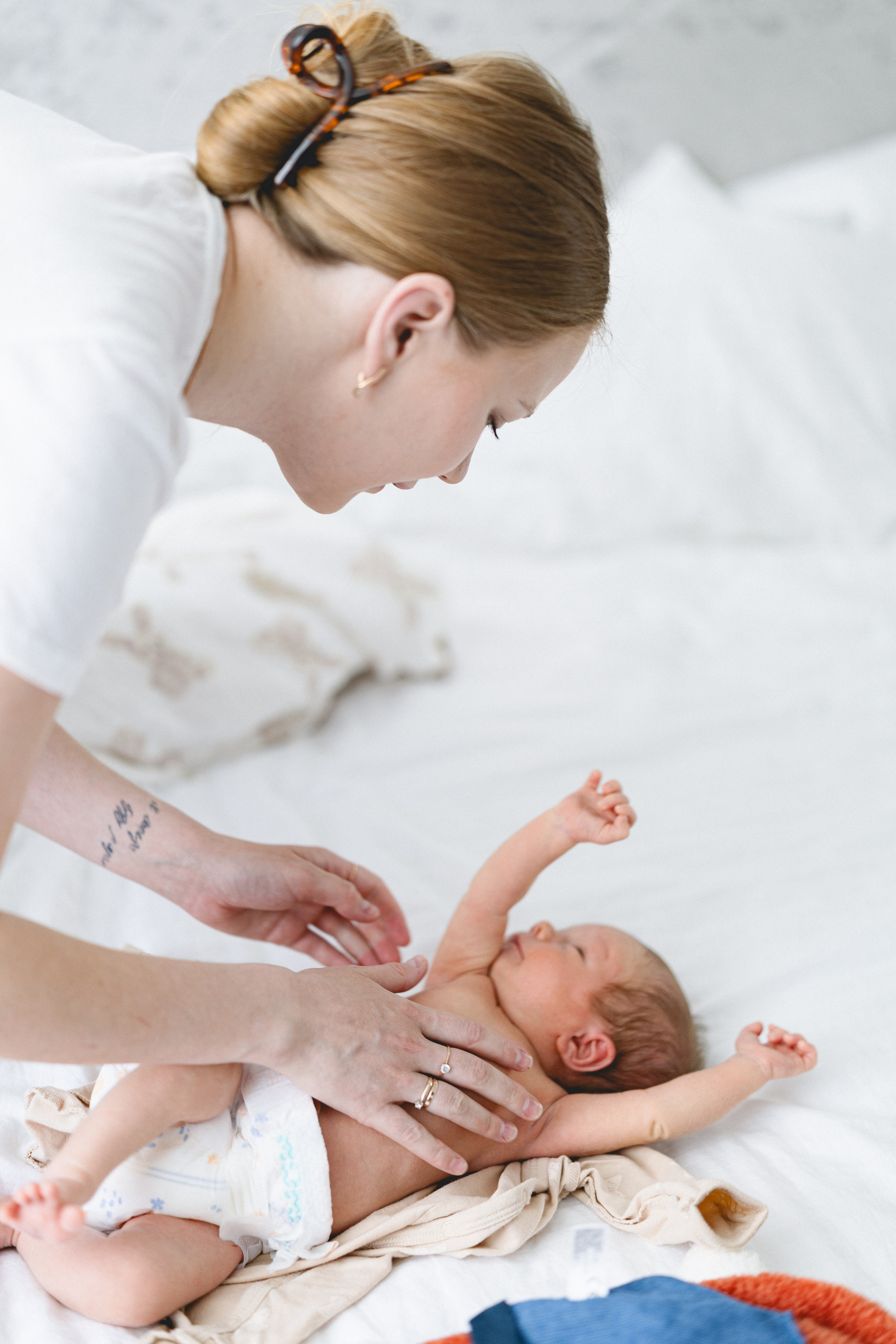Mother playing with her newborn baby on the bed