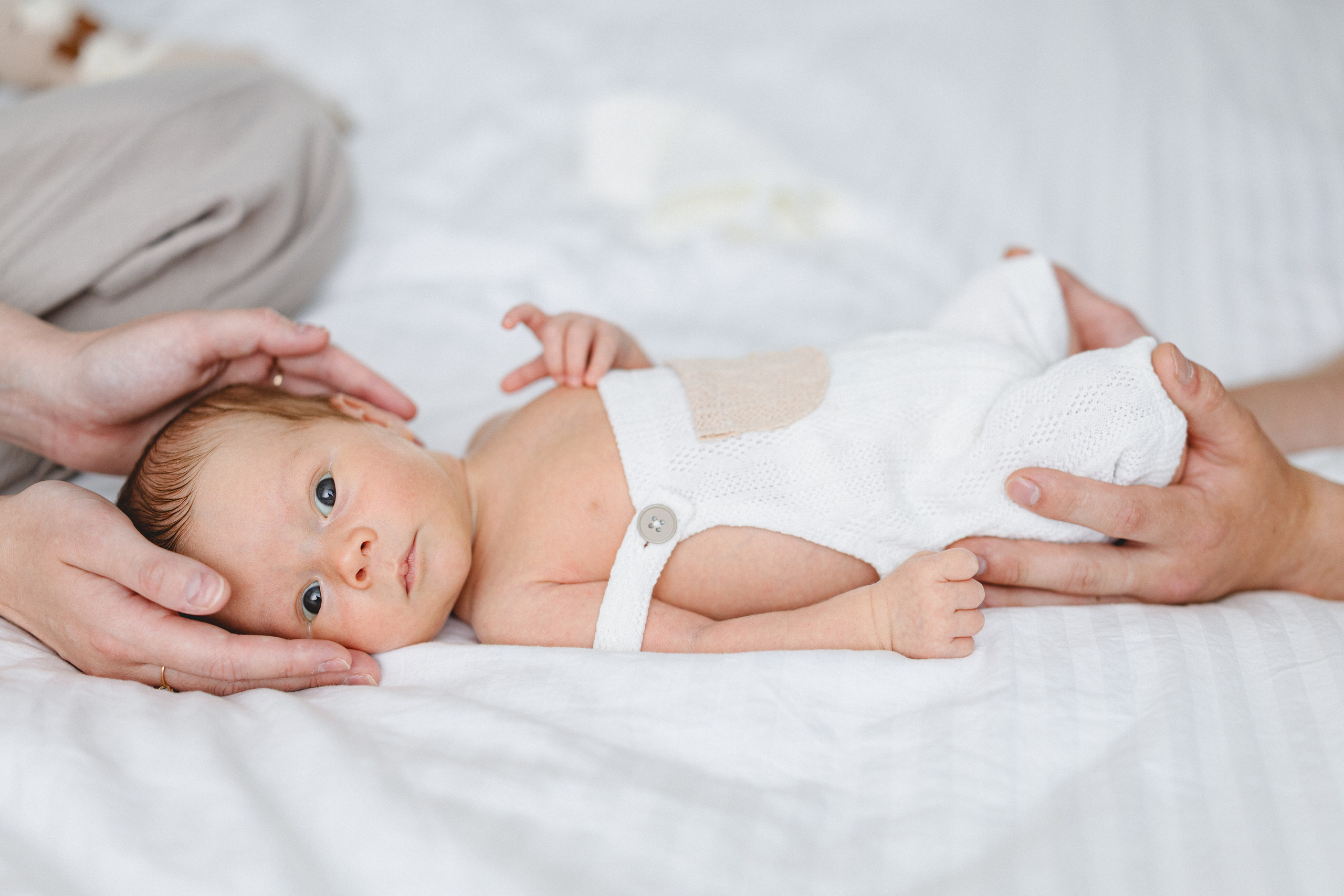 Newborn baby resting safely between the parents’ hands