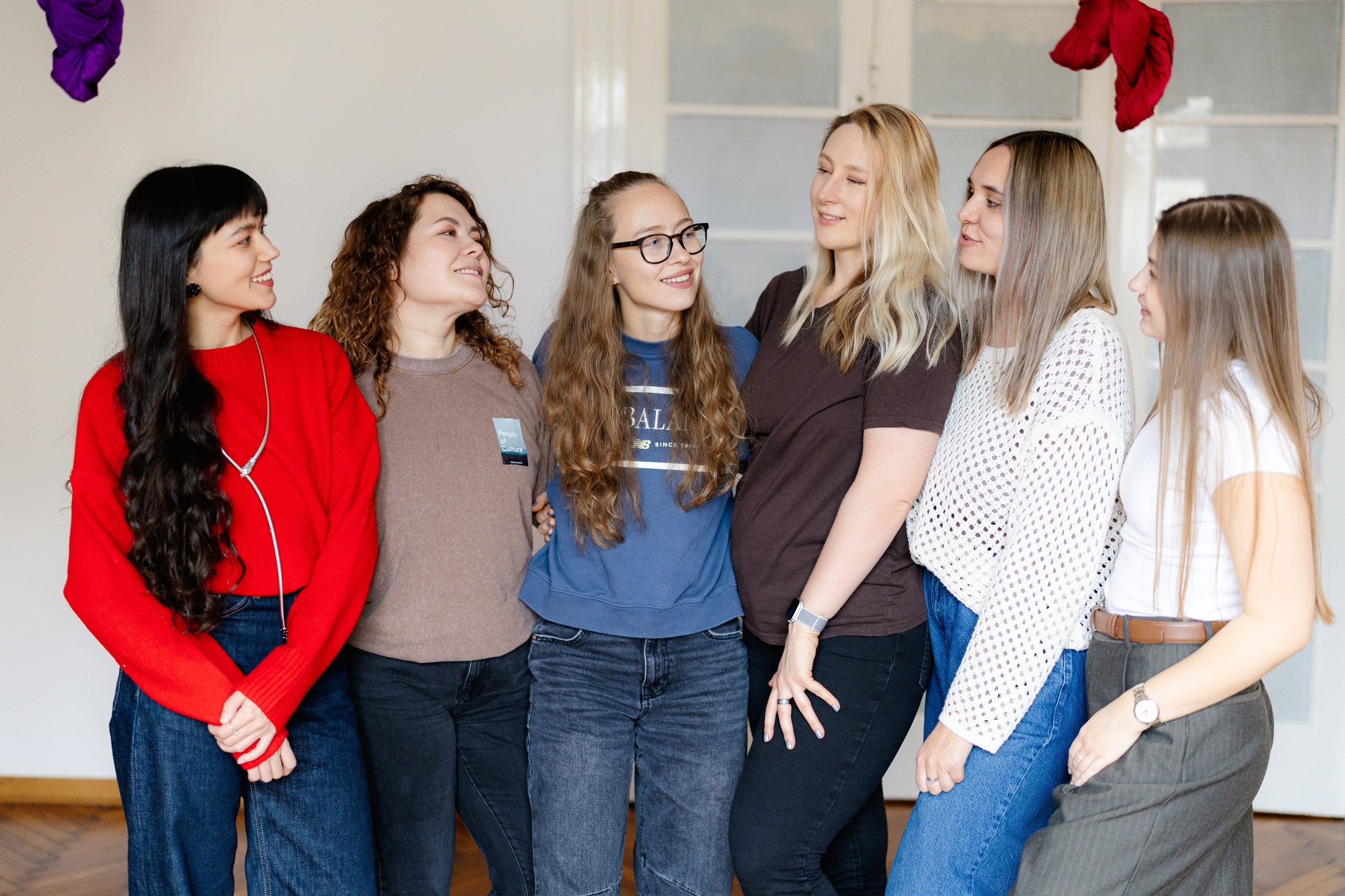 Six smiling friends and studio coaches posing together in casual clothes after training