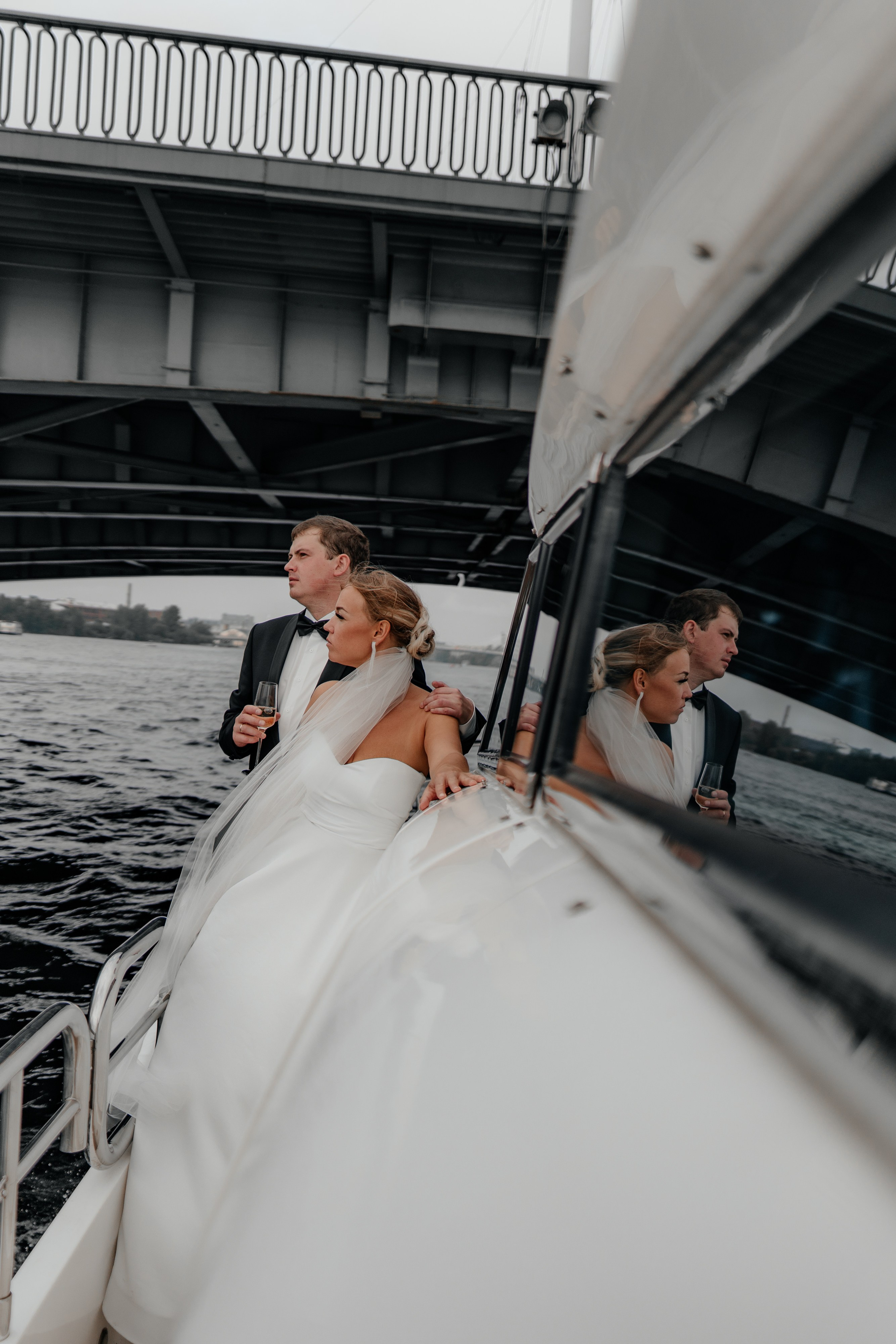 жених и невеста обнимаются на яхте на фоне моста через неву