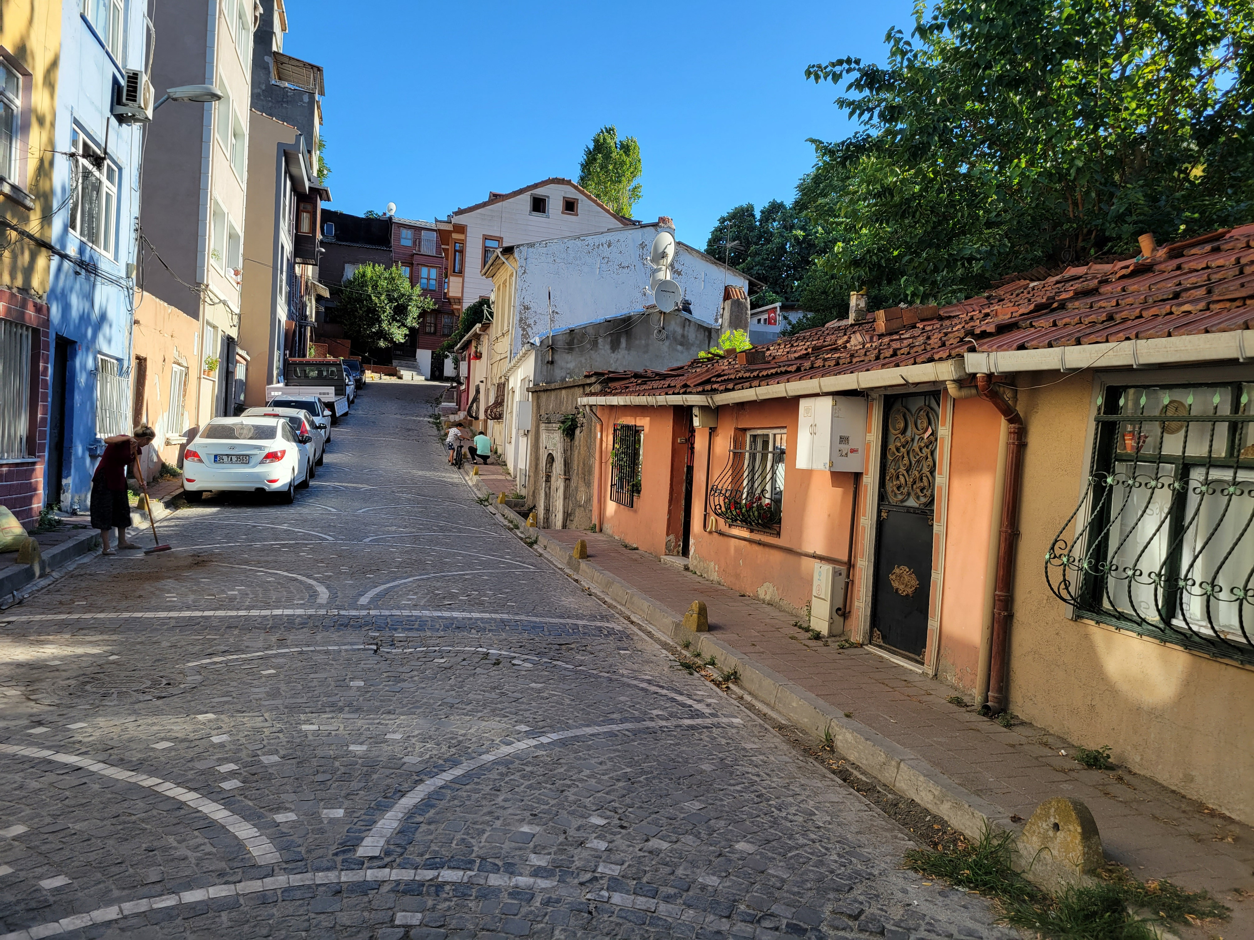 Полузаброшенные дома, при этом можно заметить - местная жительница подметает и моет дорогу перед своим домом
