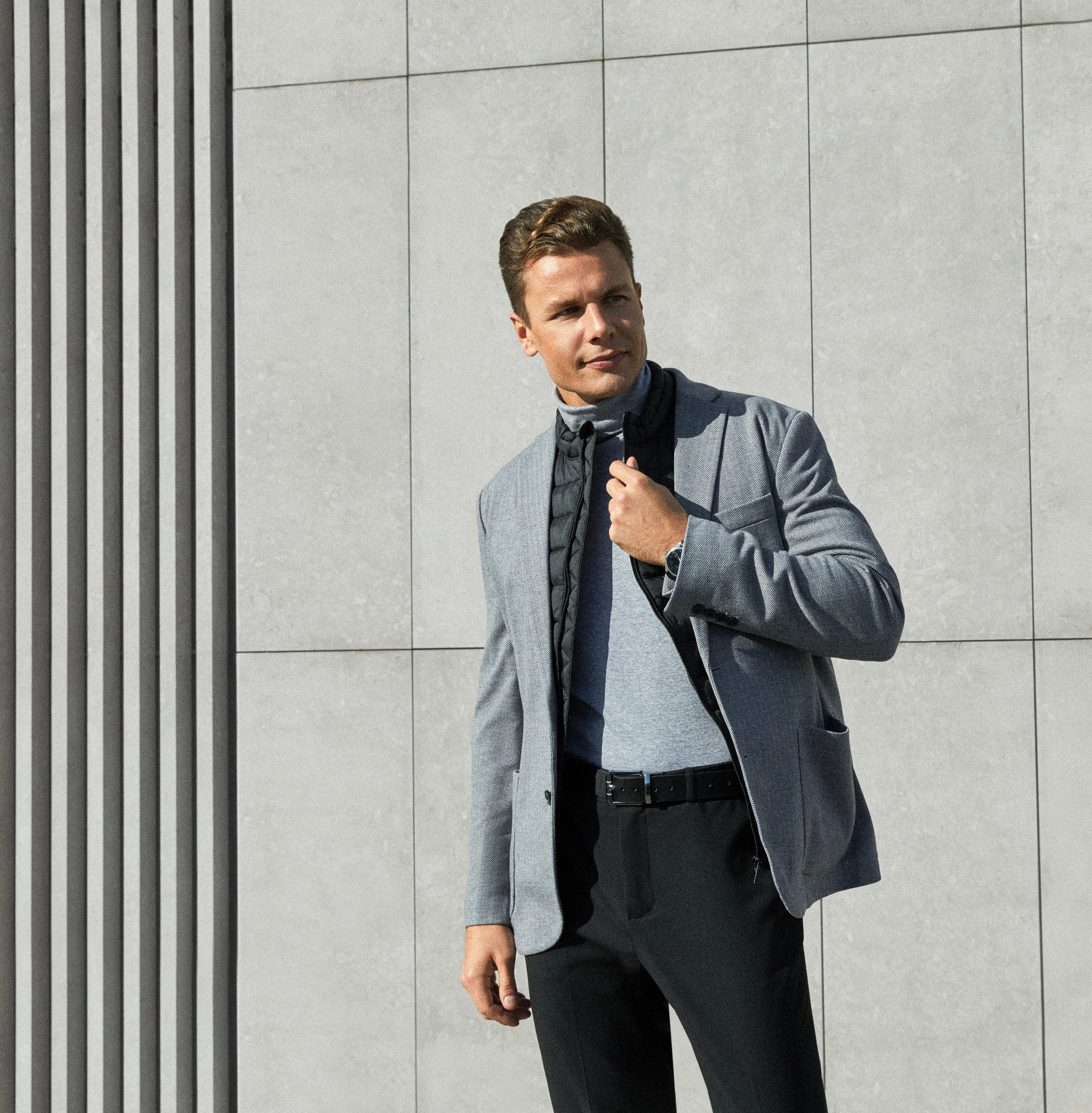 Мужчина модель в пиджаке и черных штанах на улице