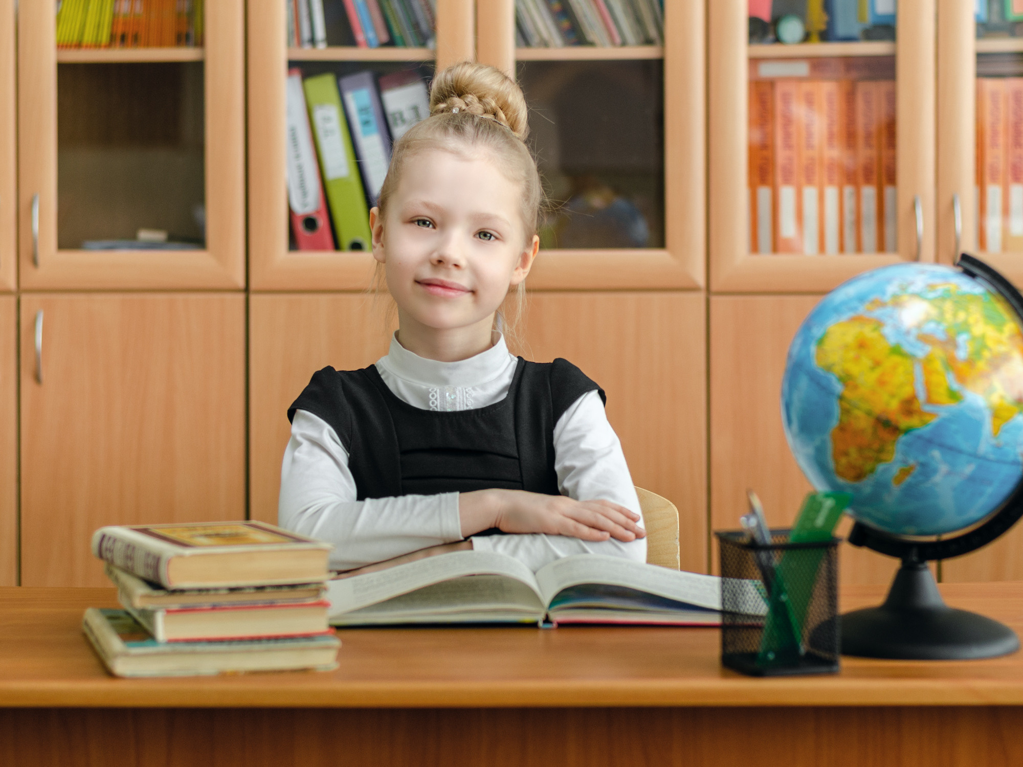 Портрет первоклассницы за партой в классе.