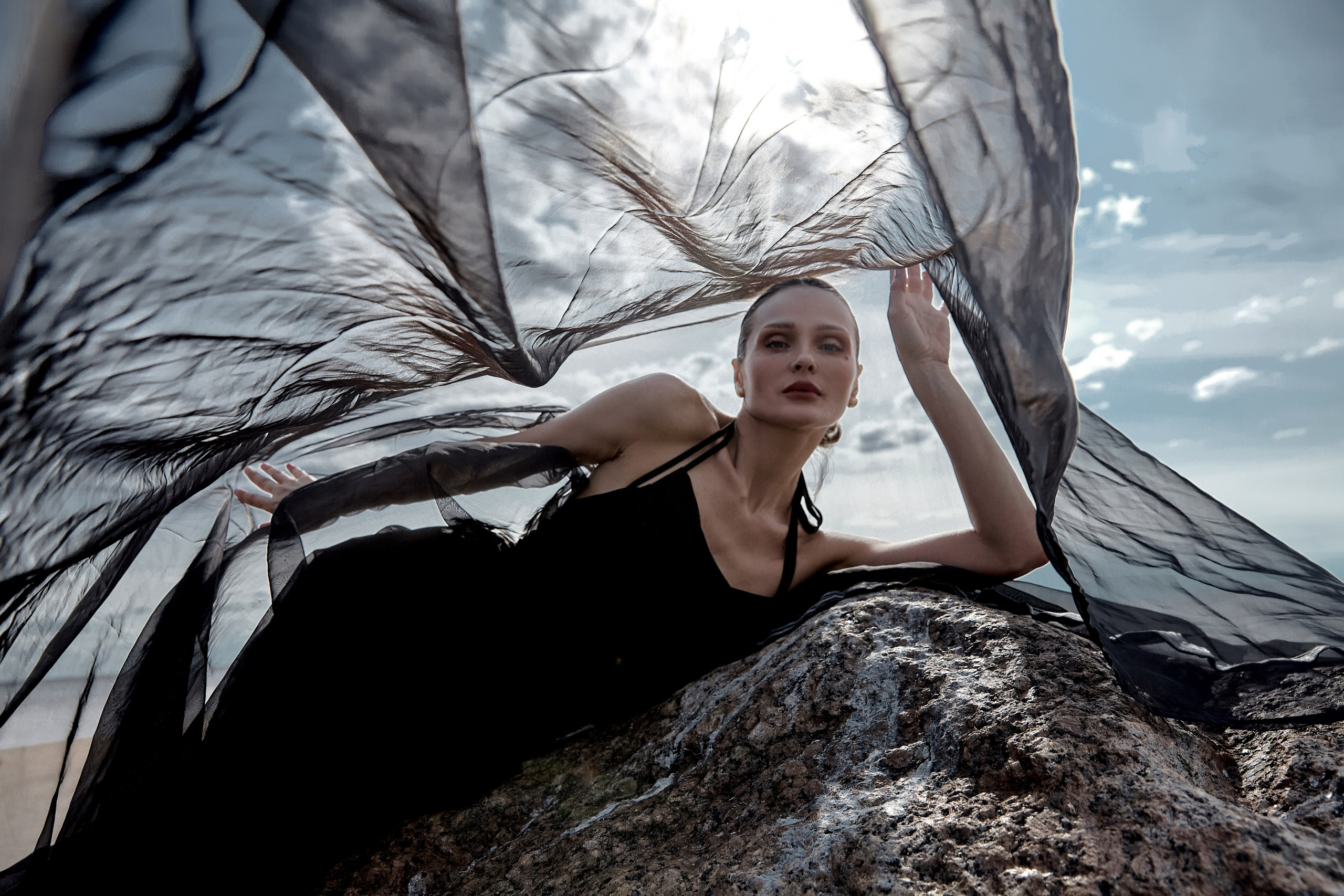 девушка на фоне неба с развивающейся черной тканью