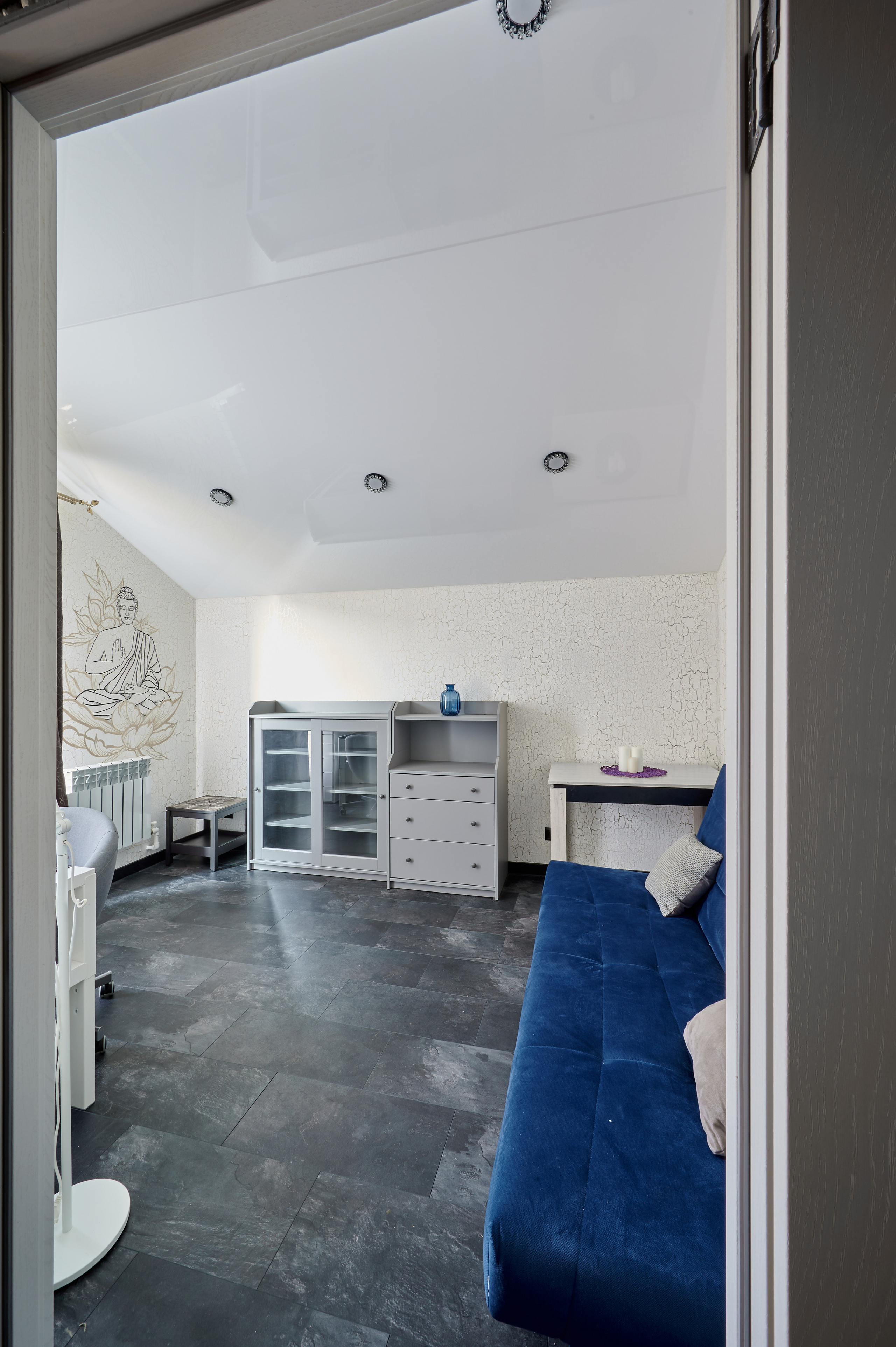 комната белые обои синий диван серая плитка на полу 