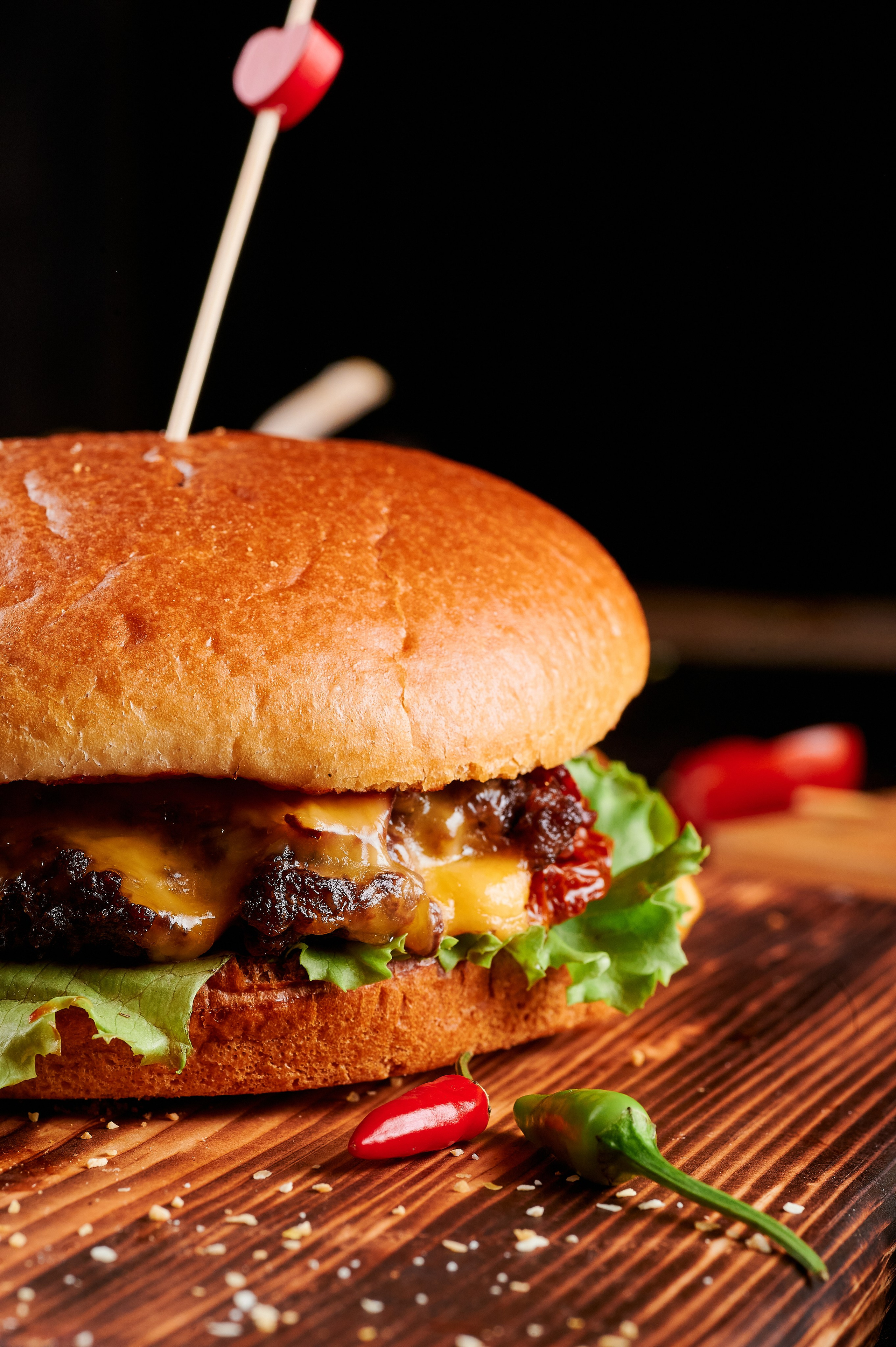 Профессиональный фуд-фотограф. Съёмка бургера для ресторана. Екатеринбург. Подача на деревянной доске, поливка соусом, свежие овощи с листьями салата