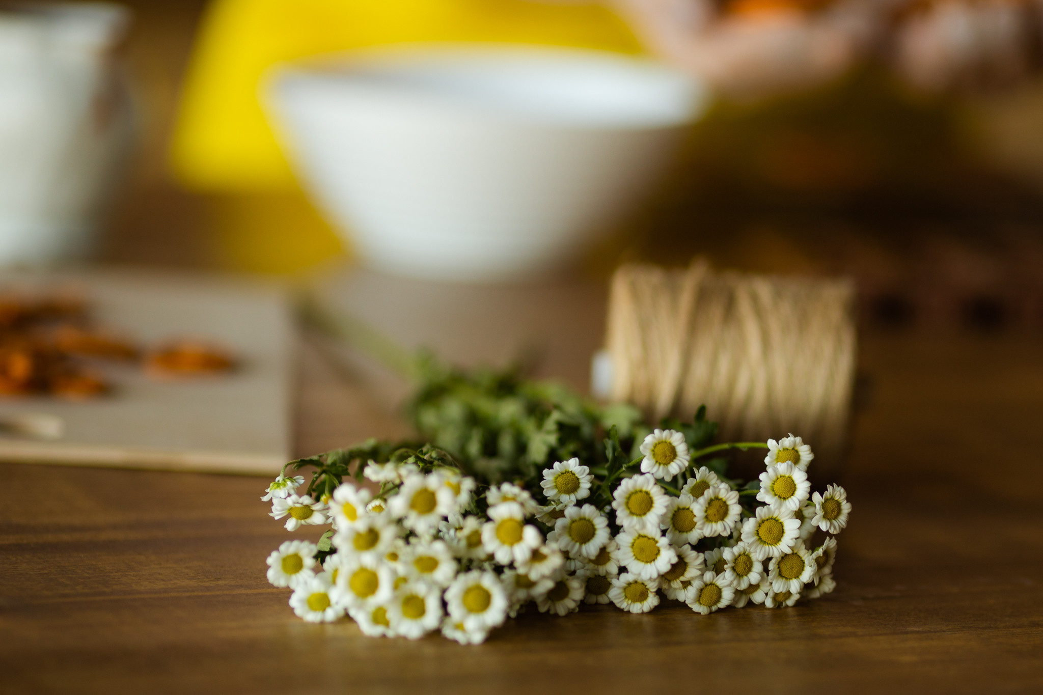 букет ромашек и катушка веревки на деревянном столе 
