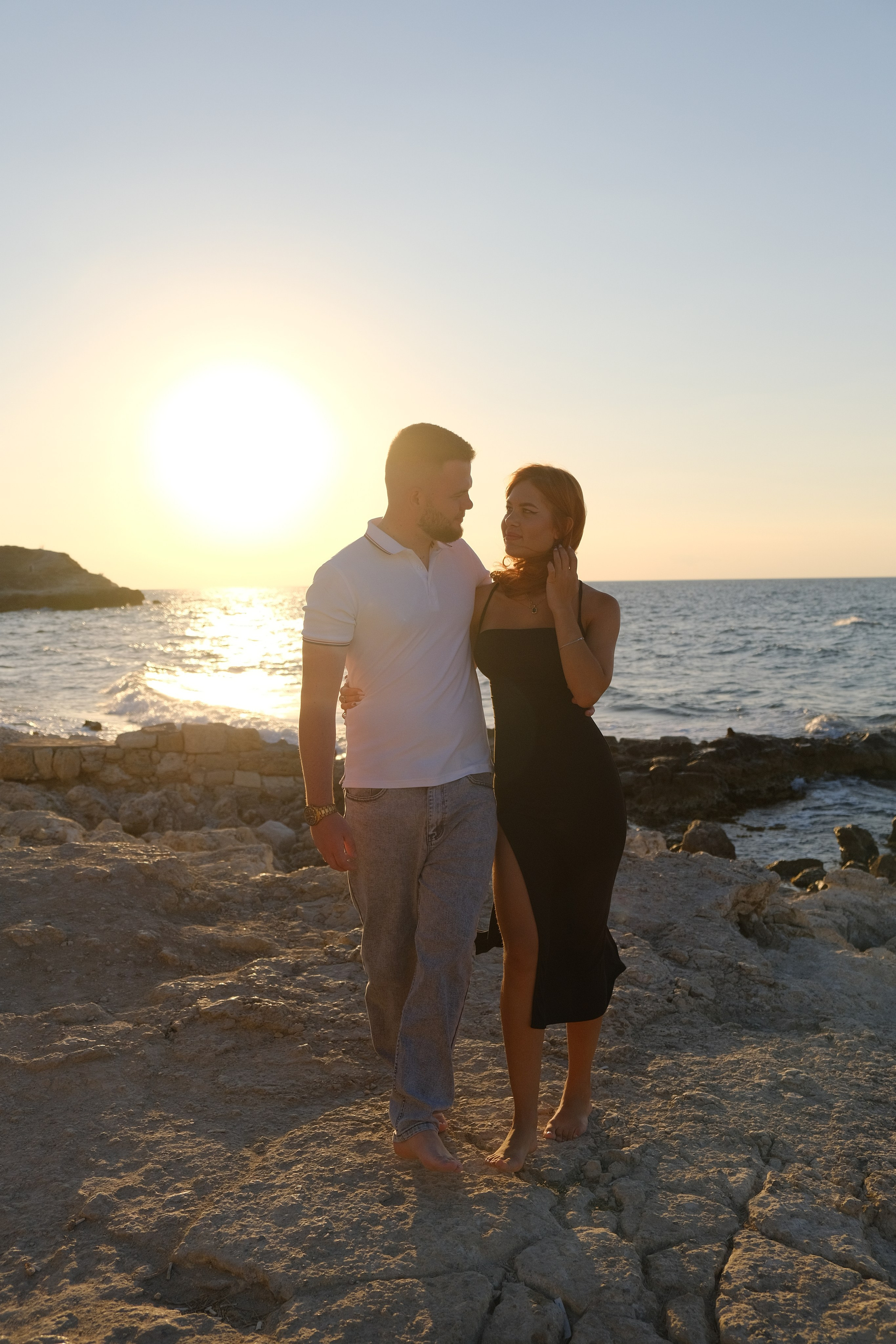 Прекрасная молодая парочка на закате стоит у моря