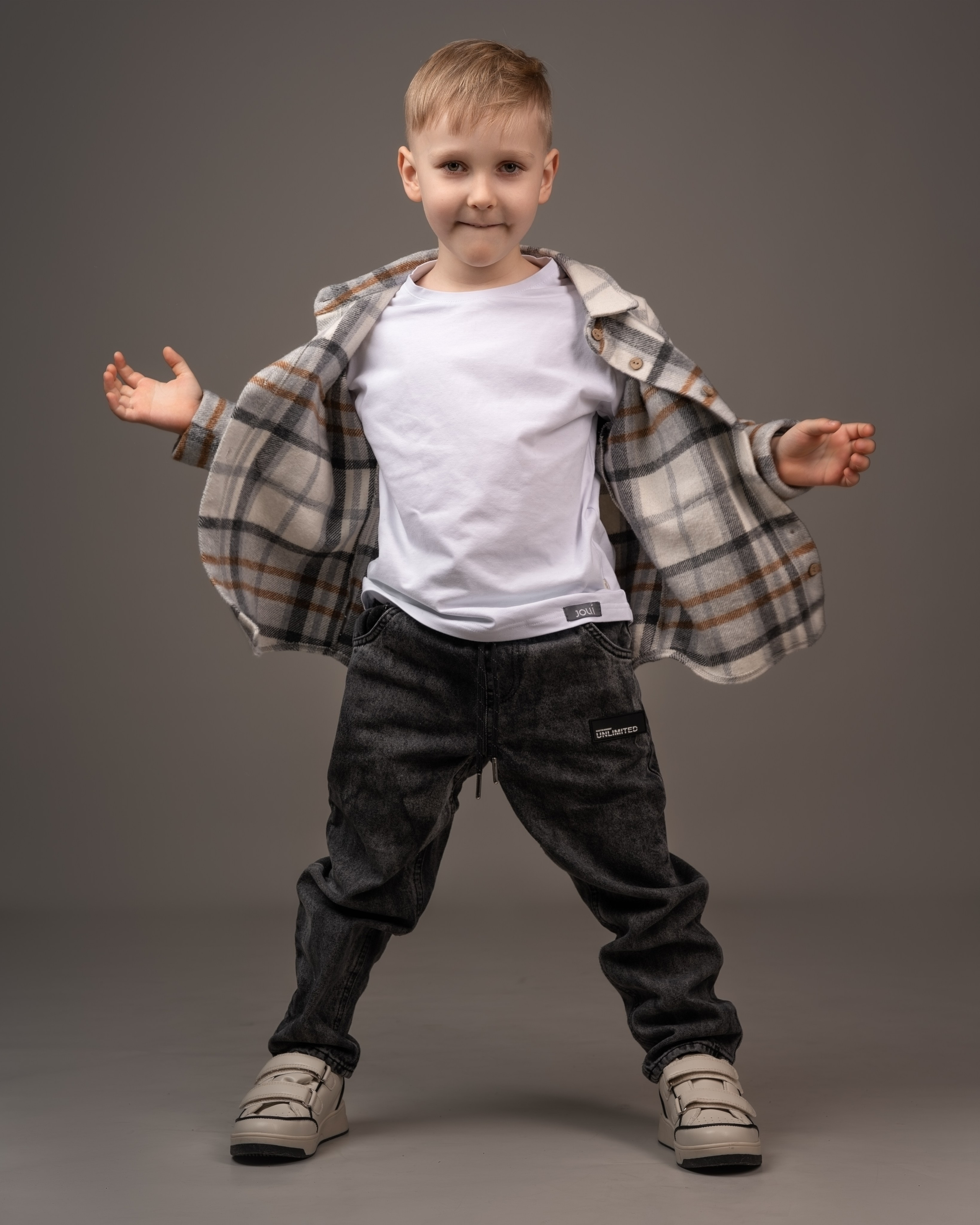 Детская фотосессия в студии. Мальчик в рубашке на сером фоне