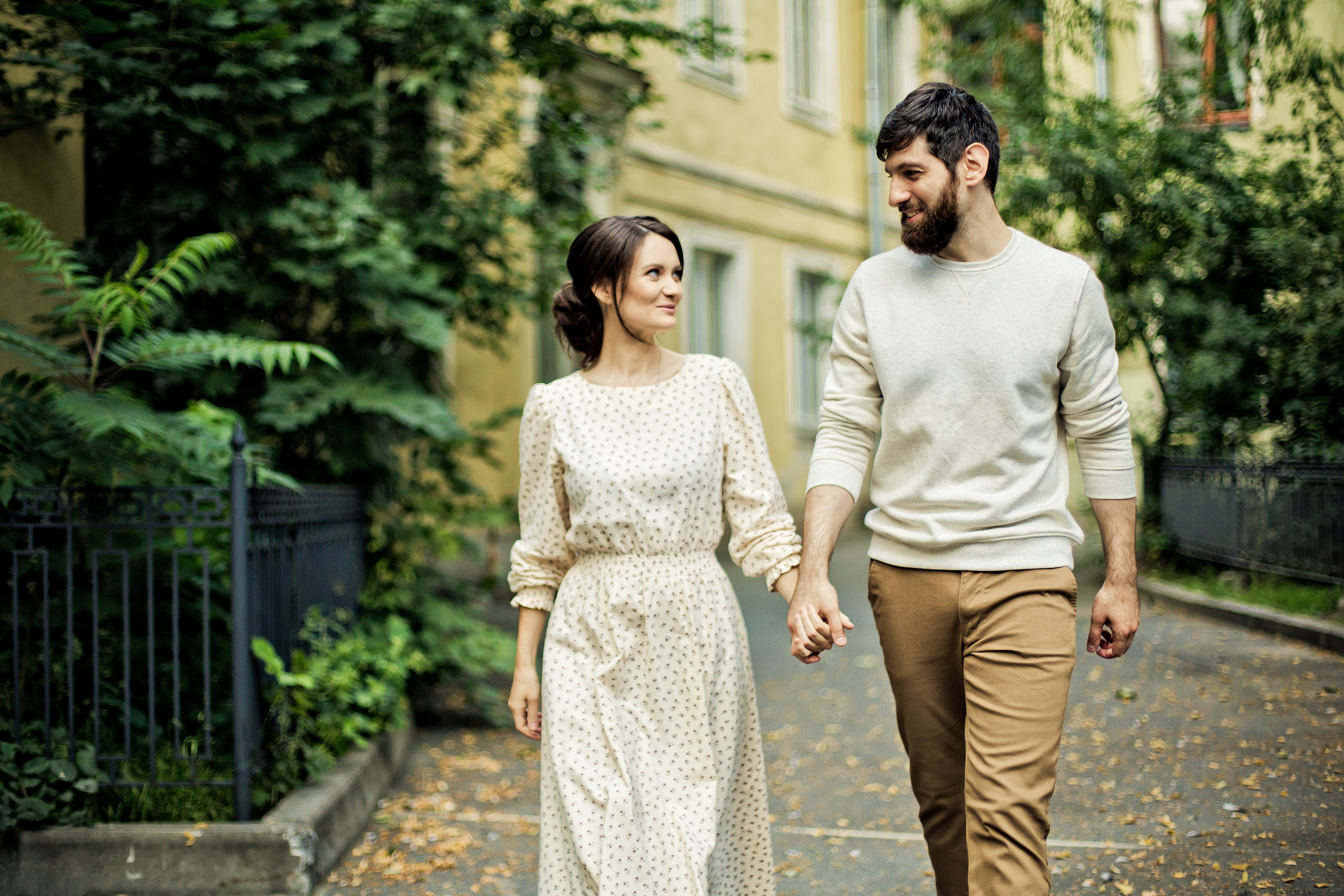 влюбленные идут взявшись за руки и смотря друг на друга через двор Петроградской