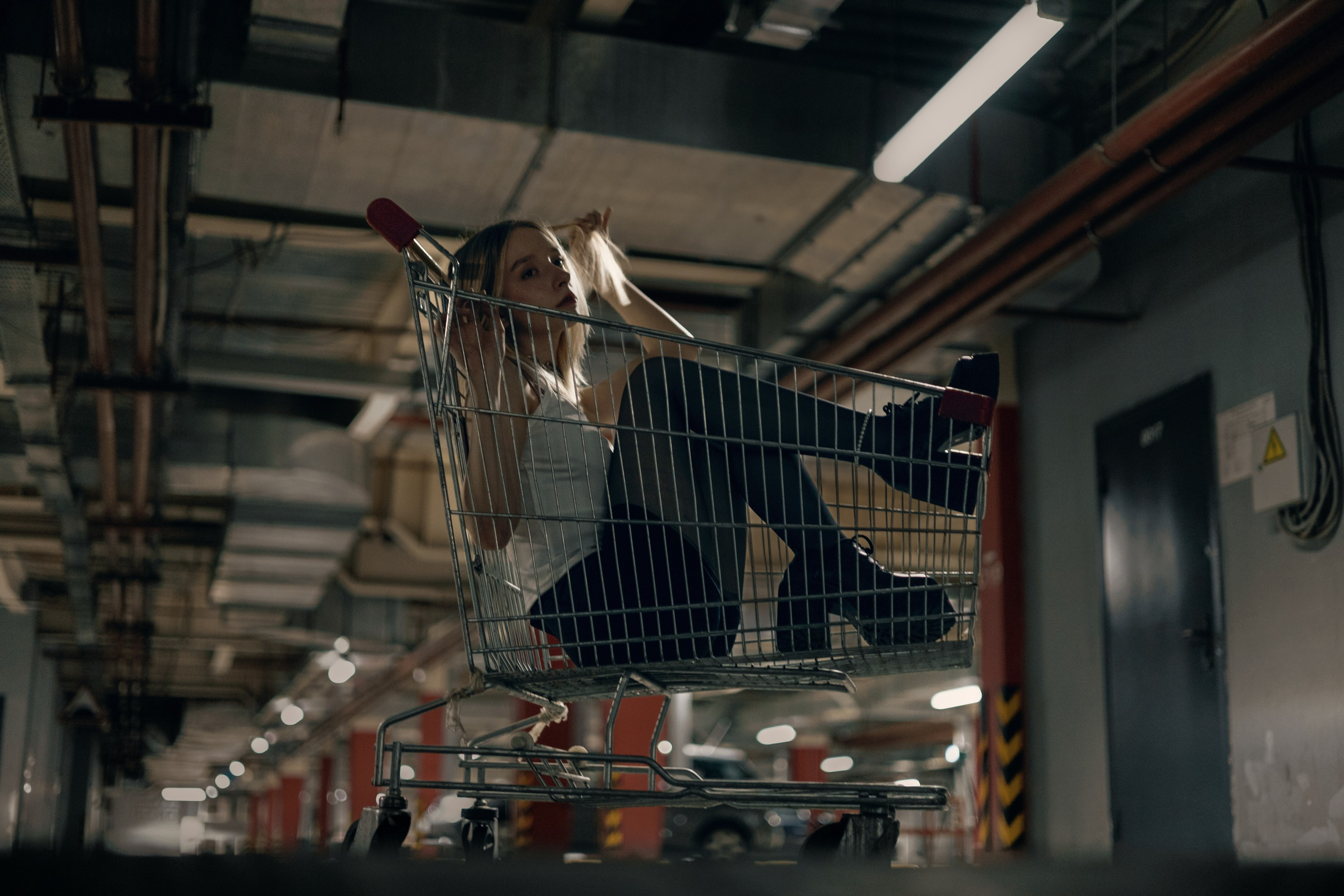 Девушка в тележке едет по парковке, фотосессия в урбанистическом стиле