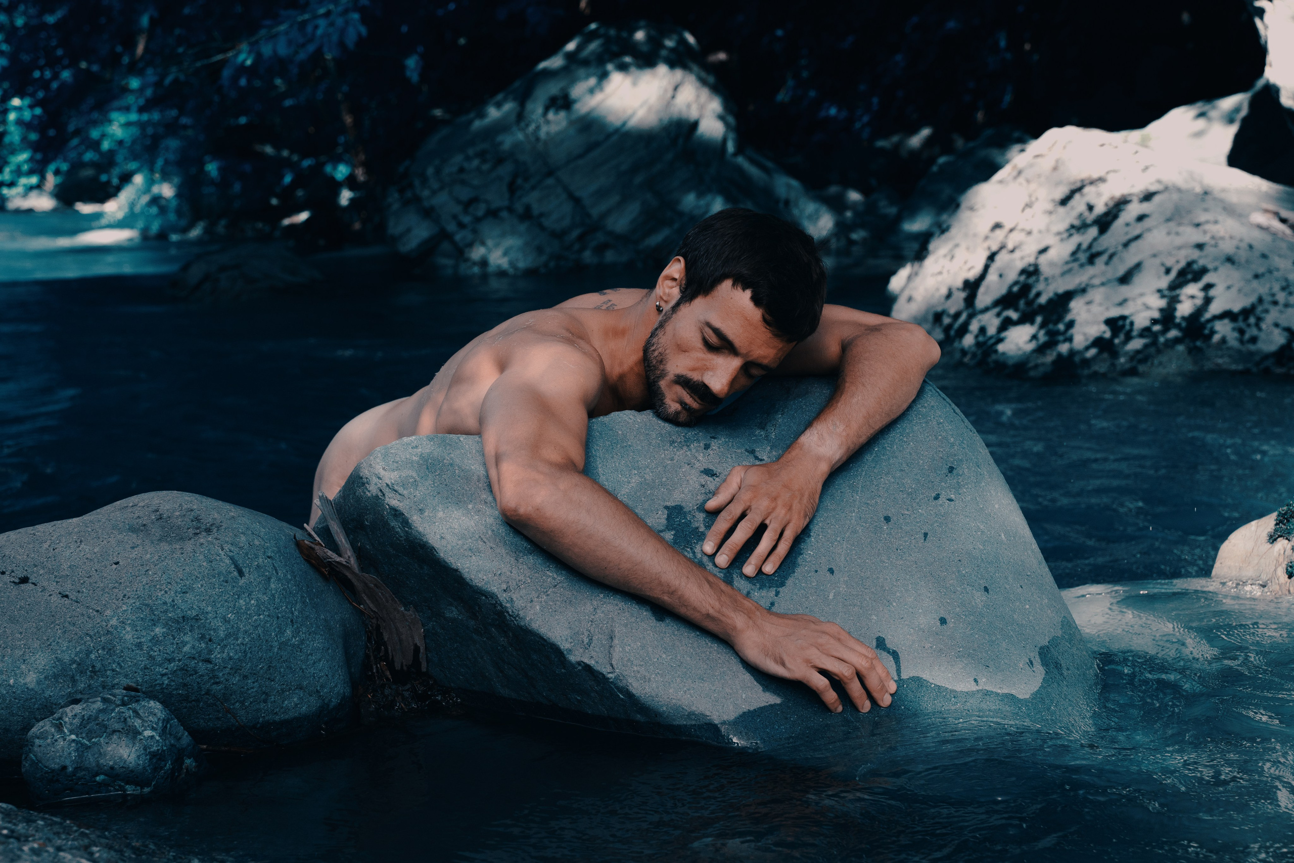 Фотография парня лежавшего на камне 