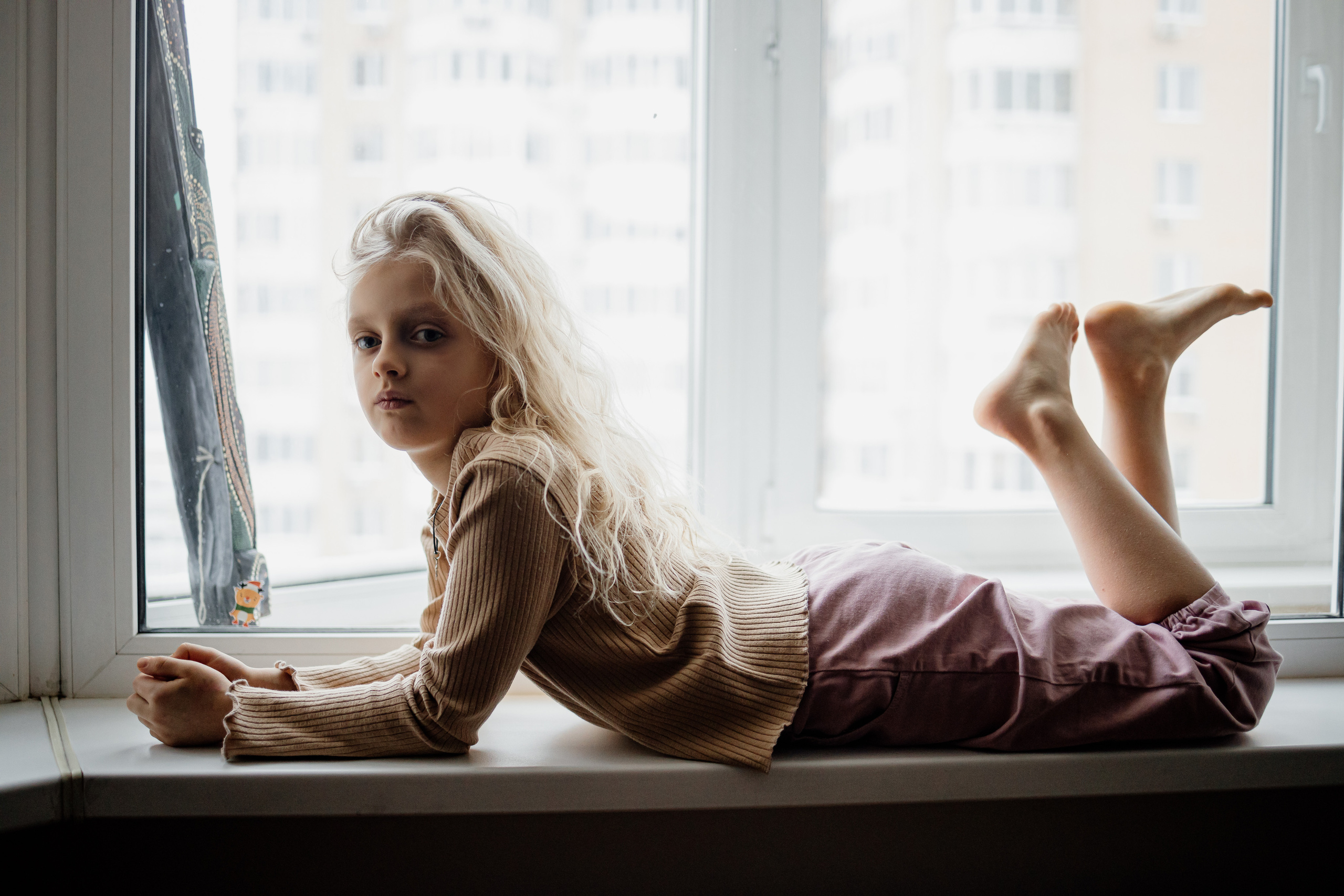 девочка лежит на подоконника смотрит в кадр