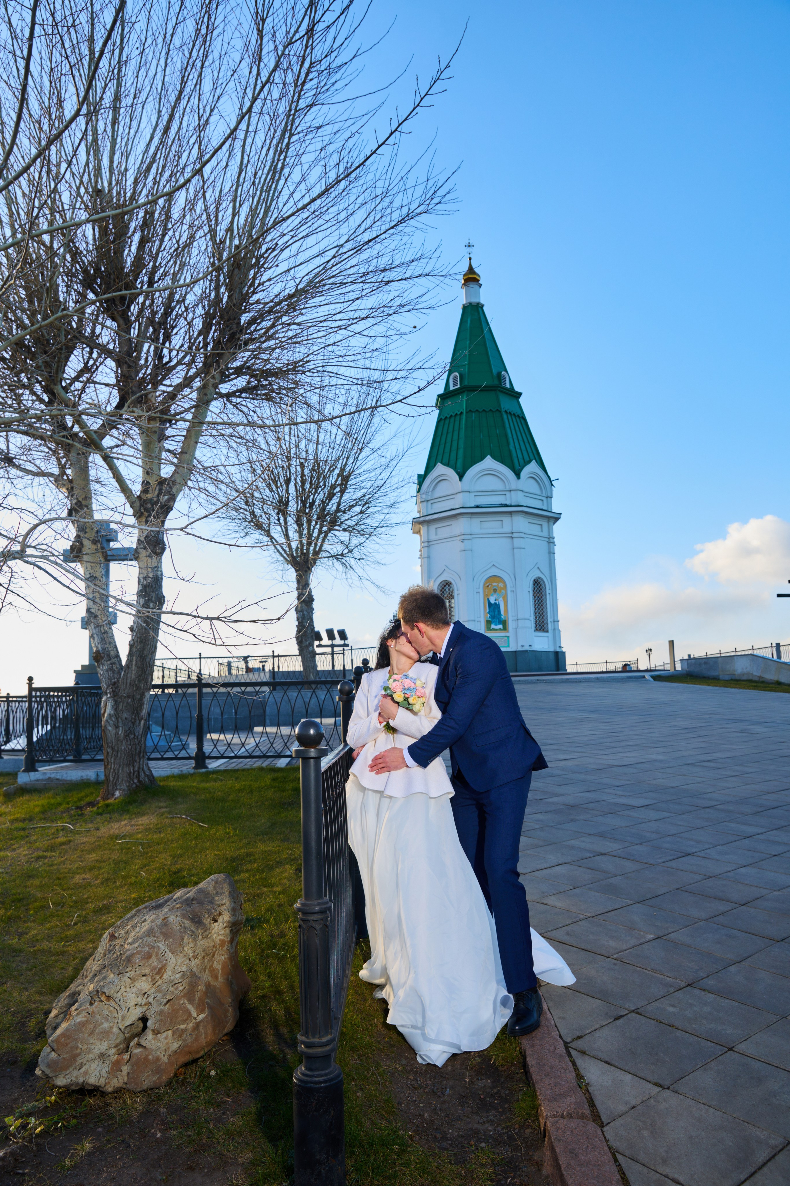 жених целует невесту на фоне часовни