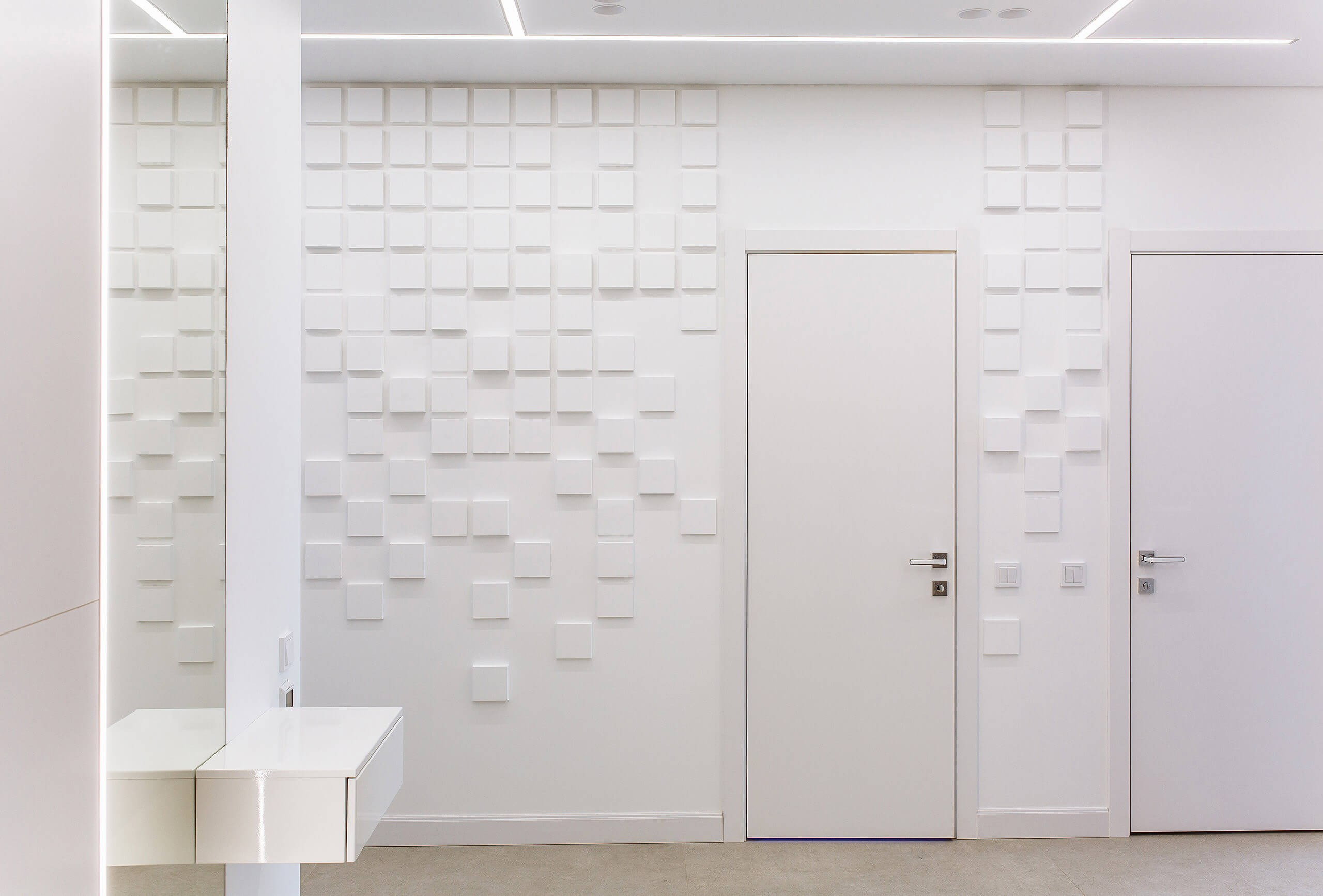 Фотография светлой прихожей в стиле минимализм: стена, декорированная объемными квадратными панелями, белые двери и подвесная консоль. Снято для проекта современной квартиры в Пензе.