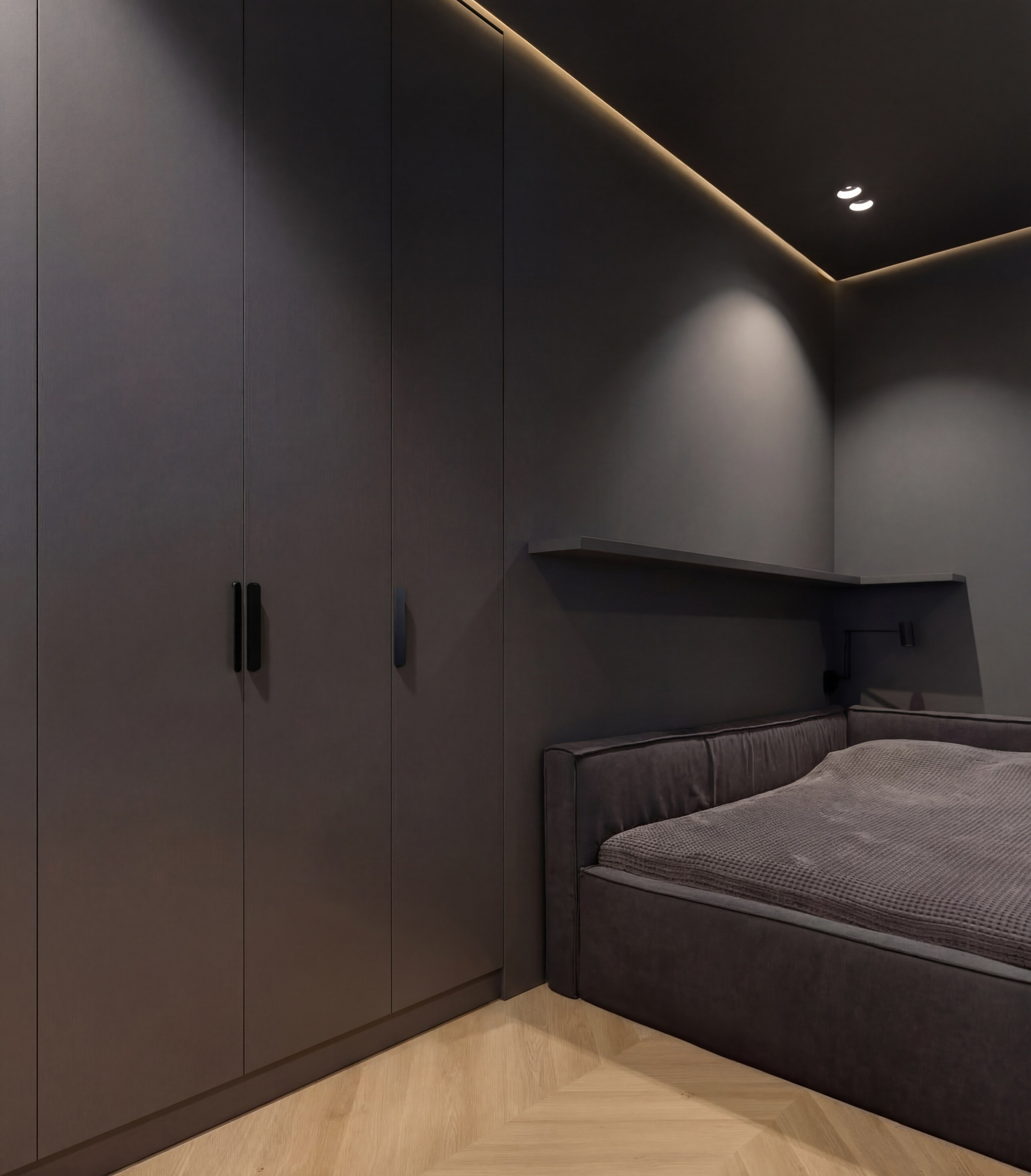 Интерьер подростковой спальни от Валерии Котович: встроенный шкаф графитового цвета, кровать с мягким изголовьем, скрытая подсветка потолка и паркет елочкой.