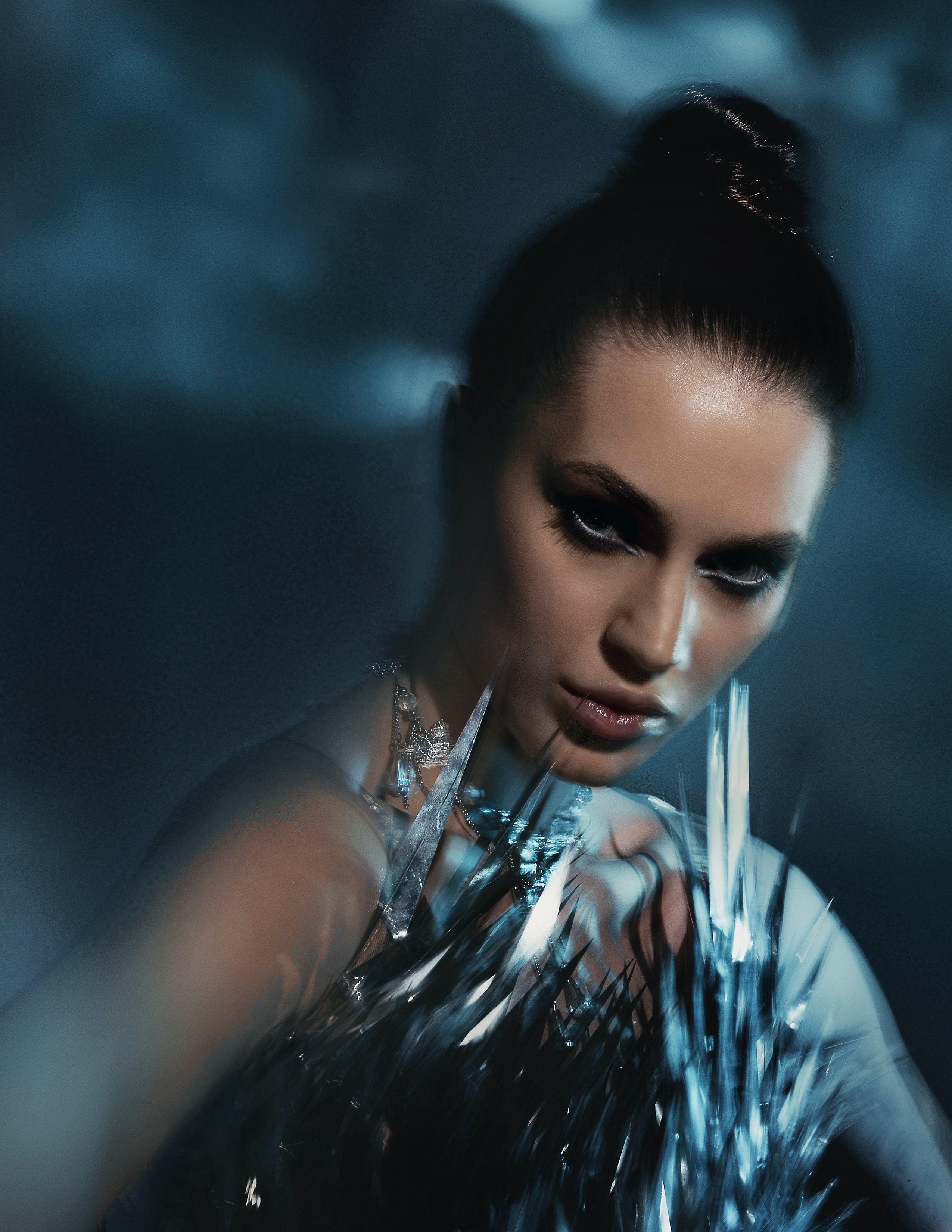 Студийная арт-съёмка в стиле Paolo Roversi. Студийный портрет девушки с темными волосами и драматичным макияжем в холодных синих тонах. Модель в платье из зеркальных осколков, имитирующих лед.  Фотограф Владивосток для фотосессии.