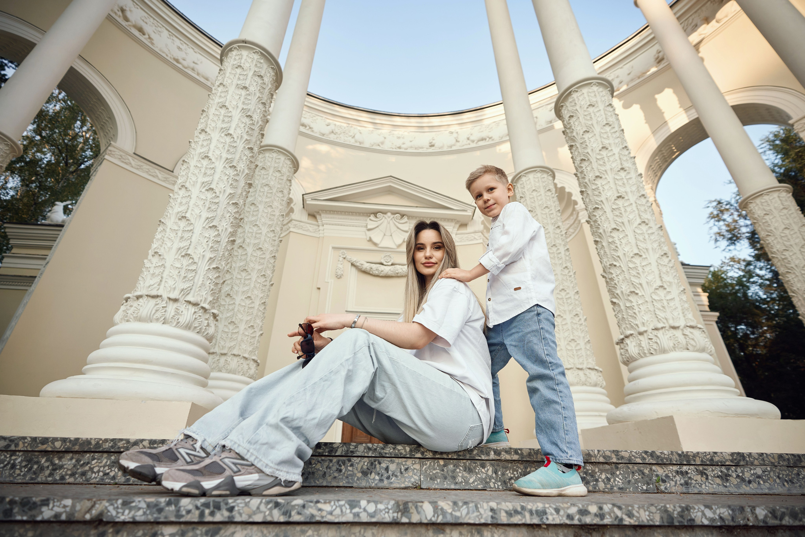 мама с сыном сидят на ступенях павильона ВДНХ, сзади высокие белые колонны