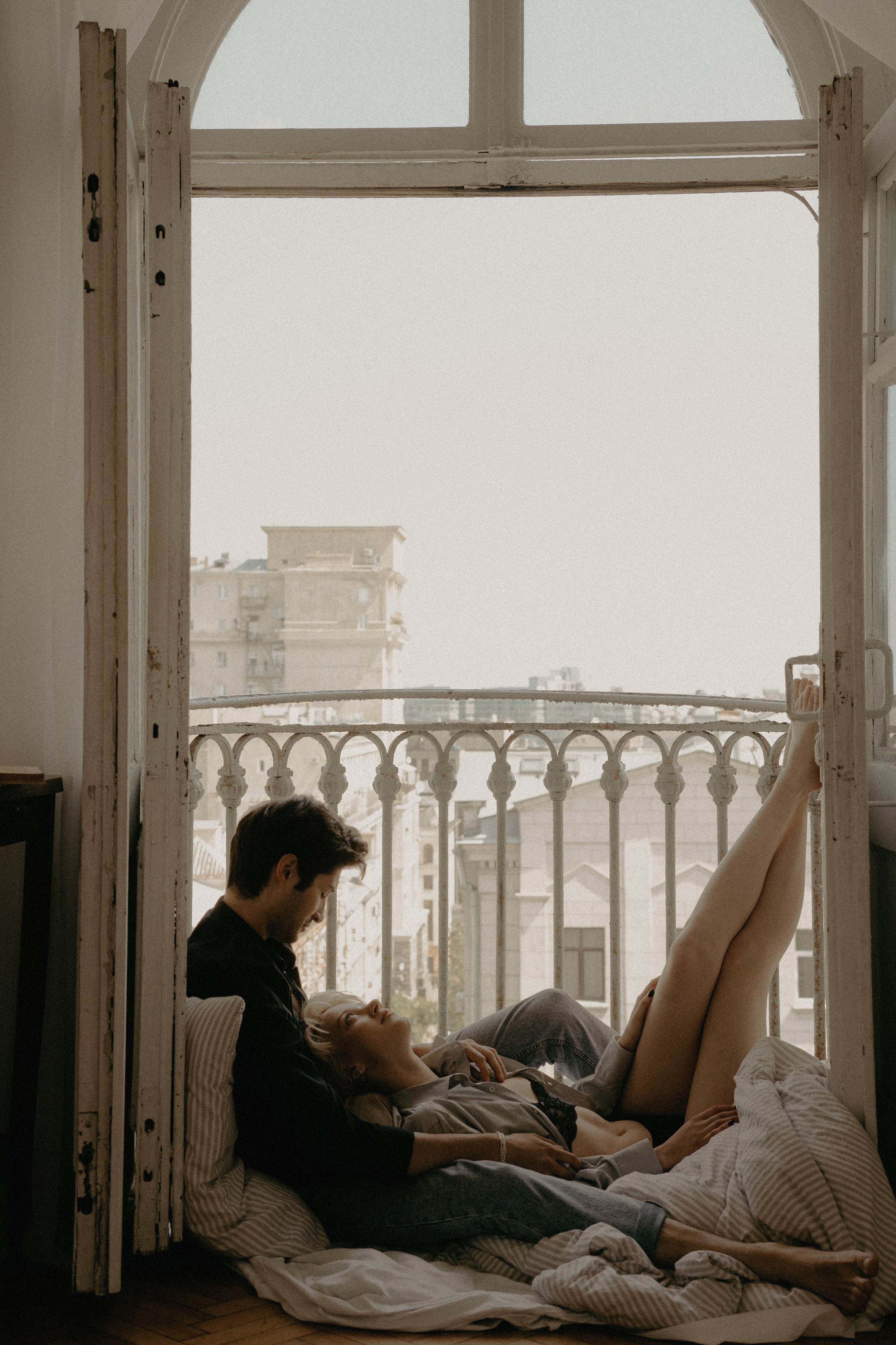 парень с девушкой лежат на балконе на полу на теплом одеяле и любуются закатом