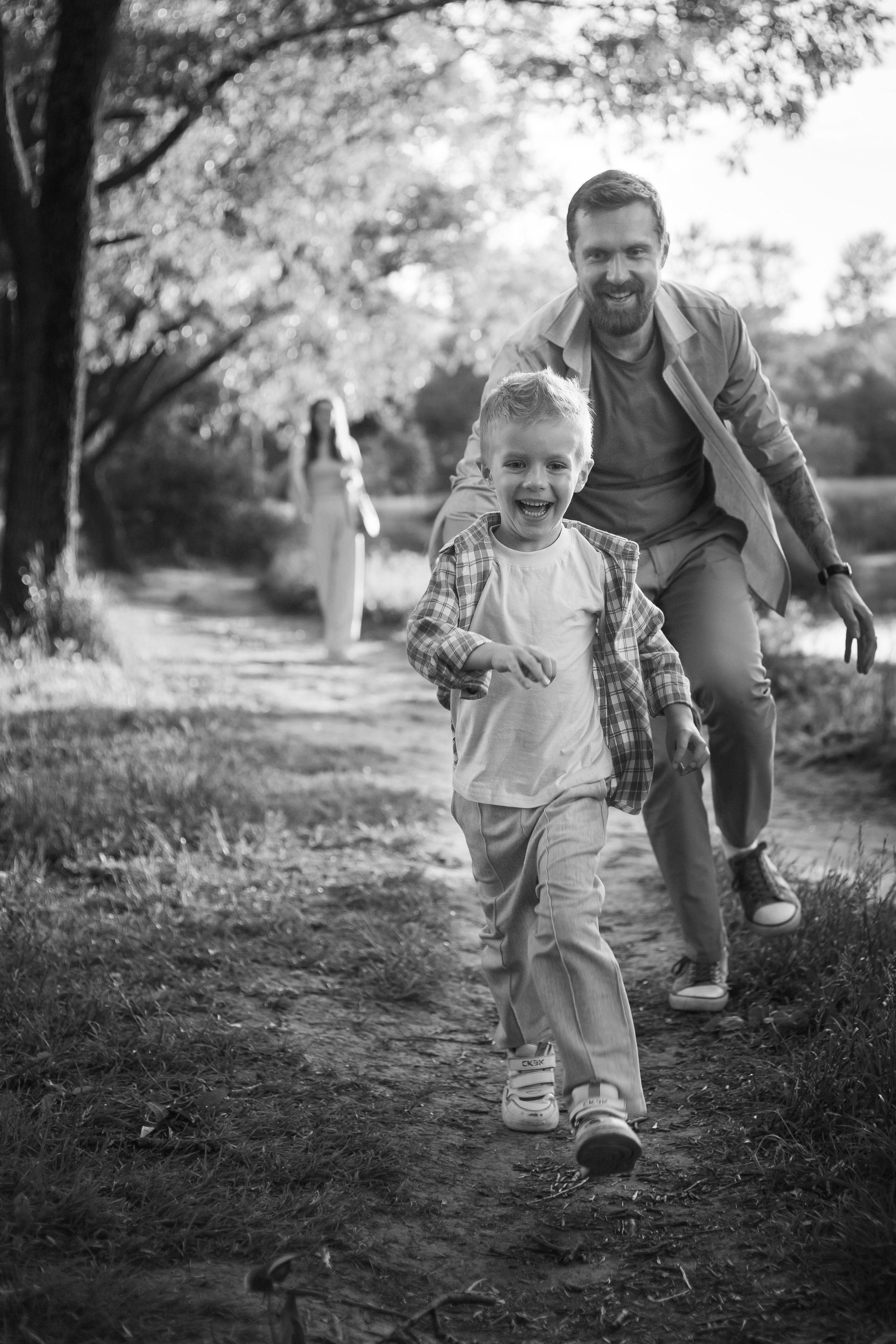 папа бежит за сыном на прогулке в парке они вместе играют вдогонялки