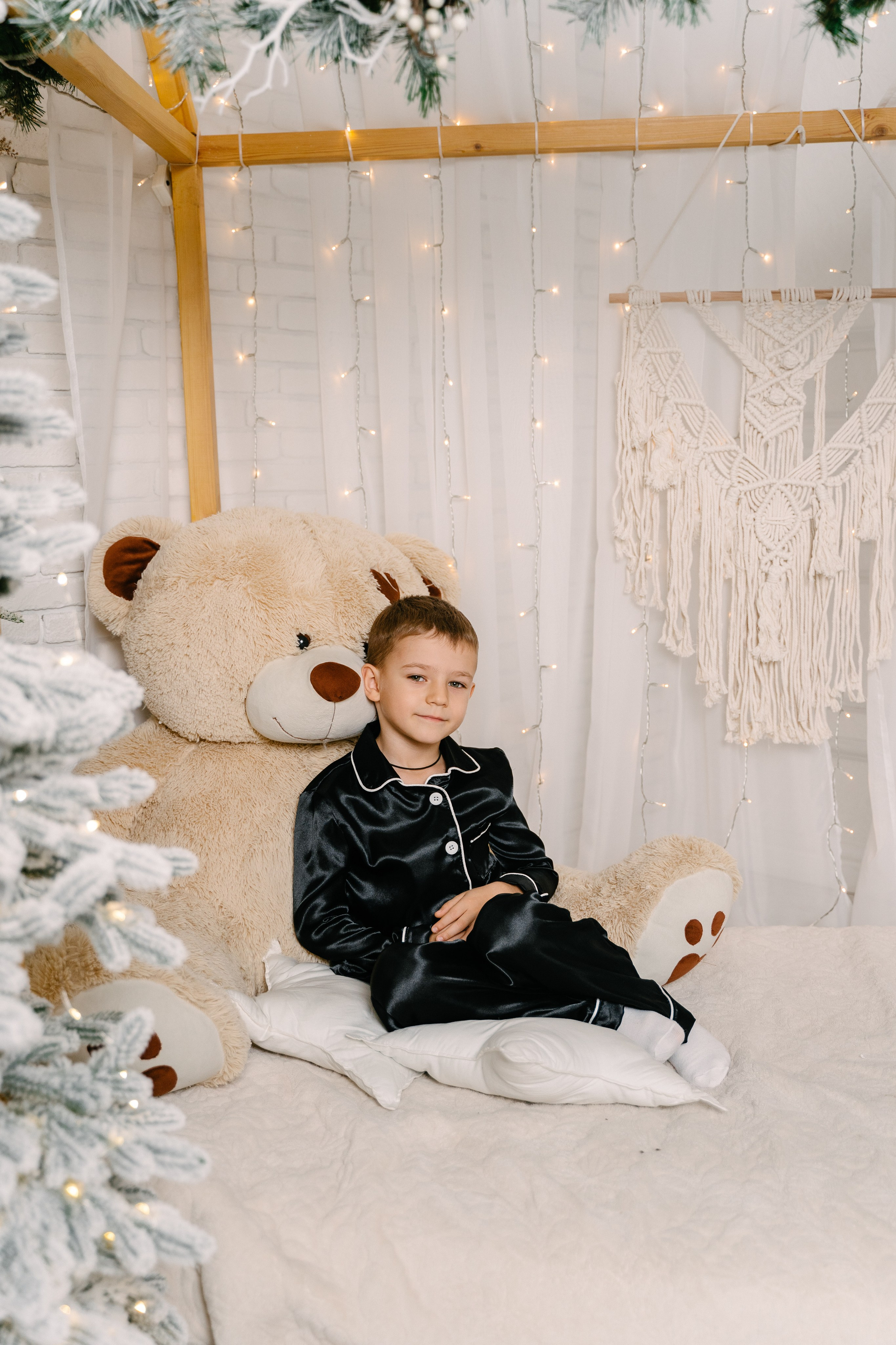 маленький мальчик сидит рядом с медведем в черной пижаме 