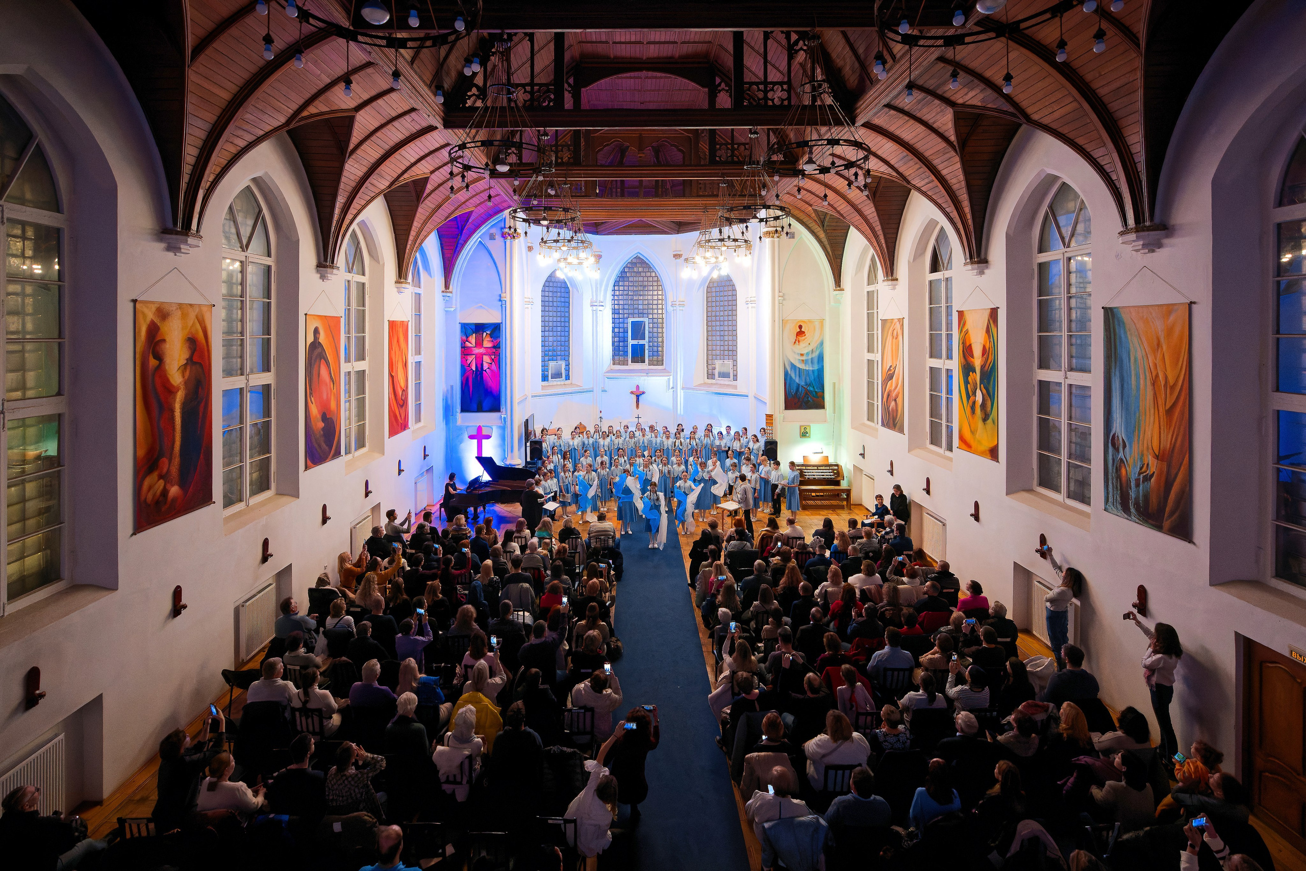 Большой хоровой концерт в зале с высокими готическими сводами - хор в синих одеждах выступает перед полной аудиторией, профессиональная съемка хоровых коллективов